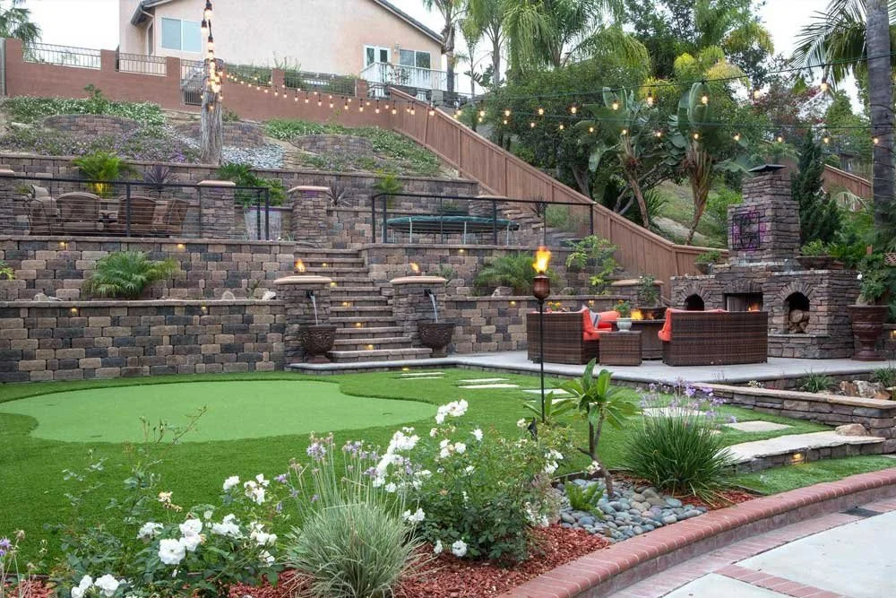 Patio area with a covered seating area, a dining table with chairs, and a landscaped garden with shrubs and planters.
