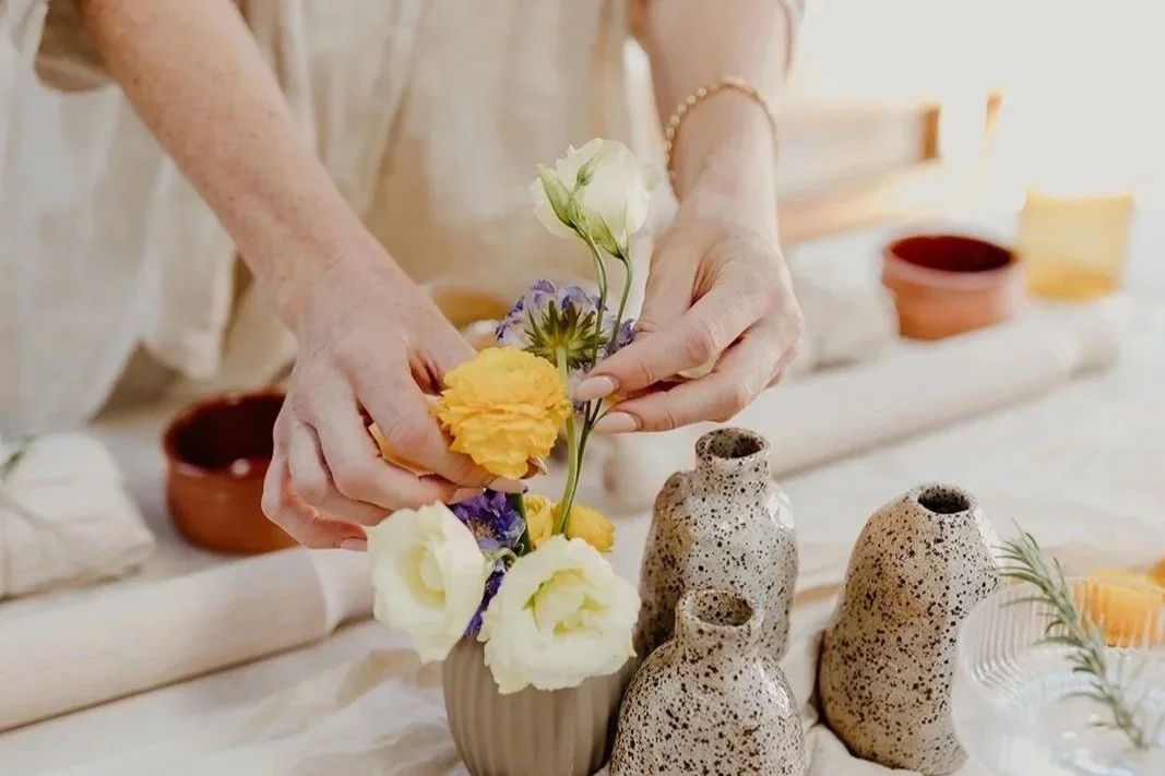 Arranging flowers beside handmade speckled bud vases at a Happy Hub Collective pottery workshop in Fremantle