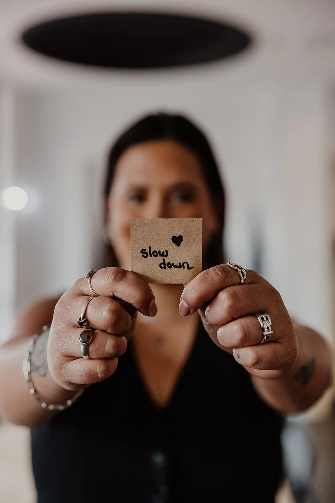 Happy Hub Collective staff member holding a “slow down” sign inside the Fremantle pottery studio in Perth.