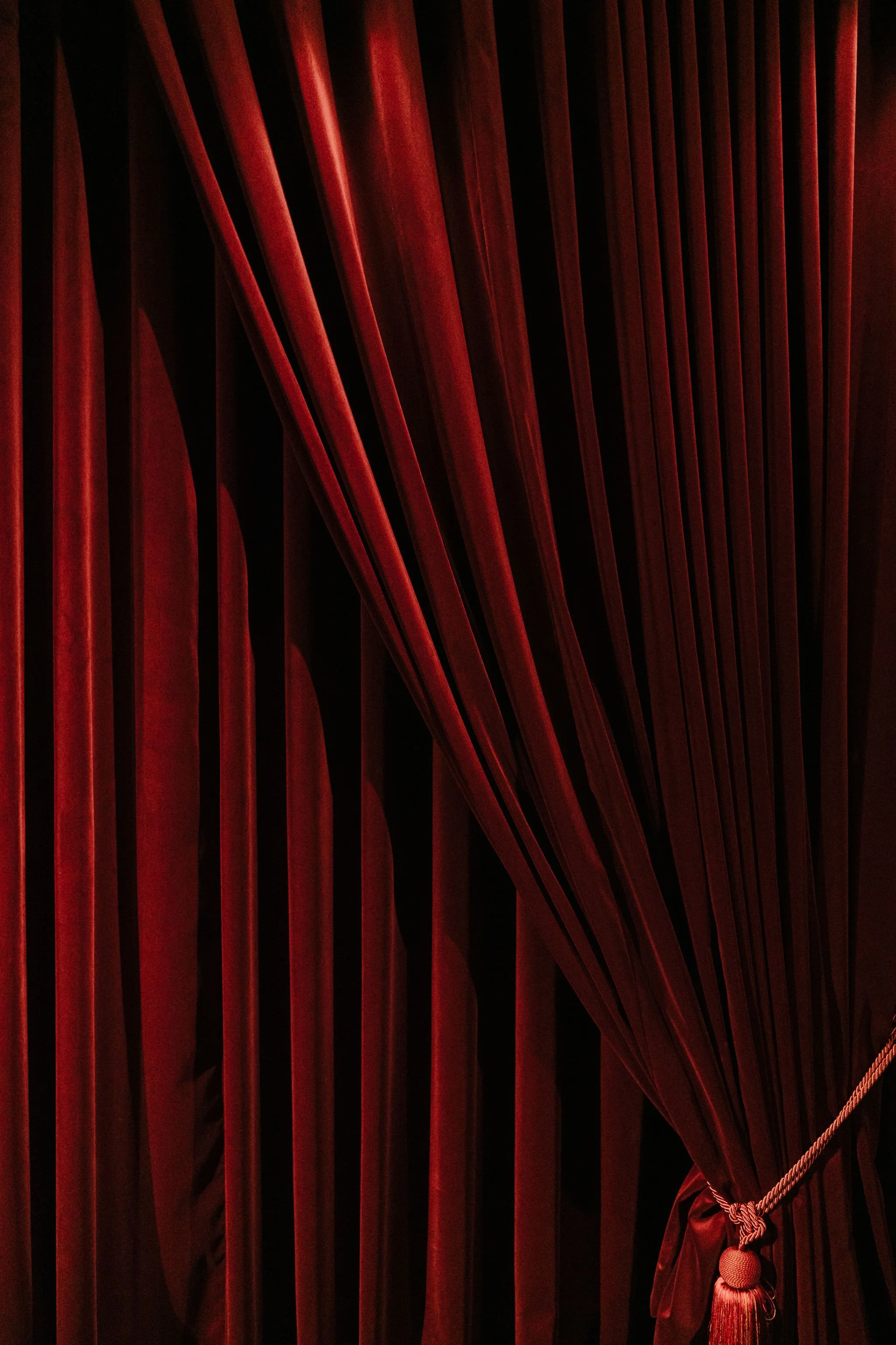 Red theatre curtains with a gathered curtain tie on the right side.