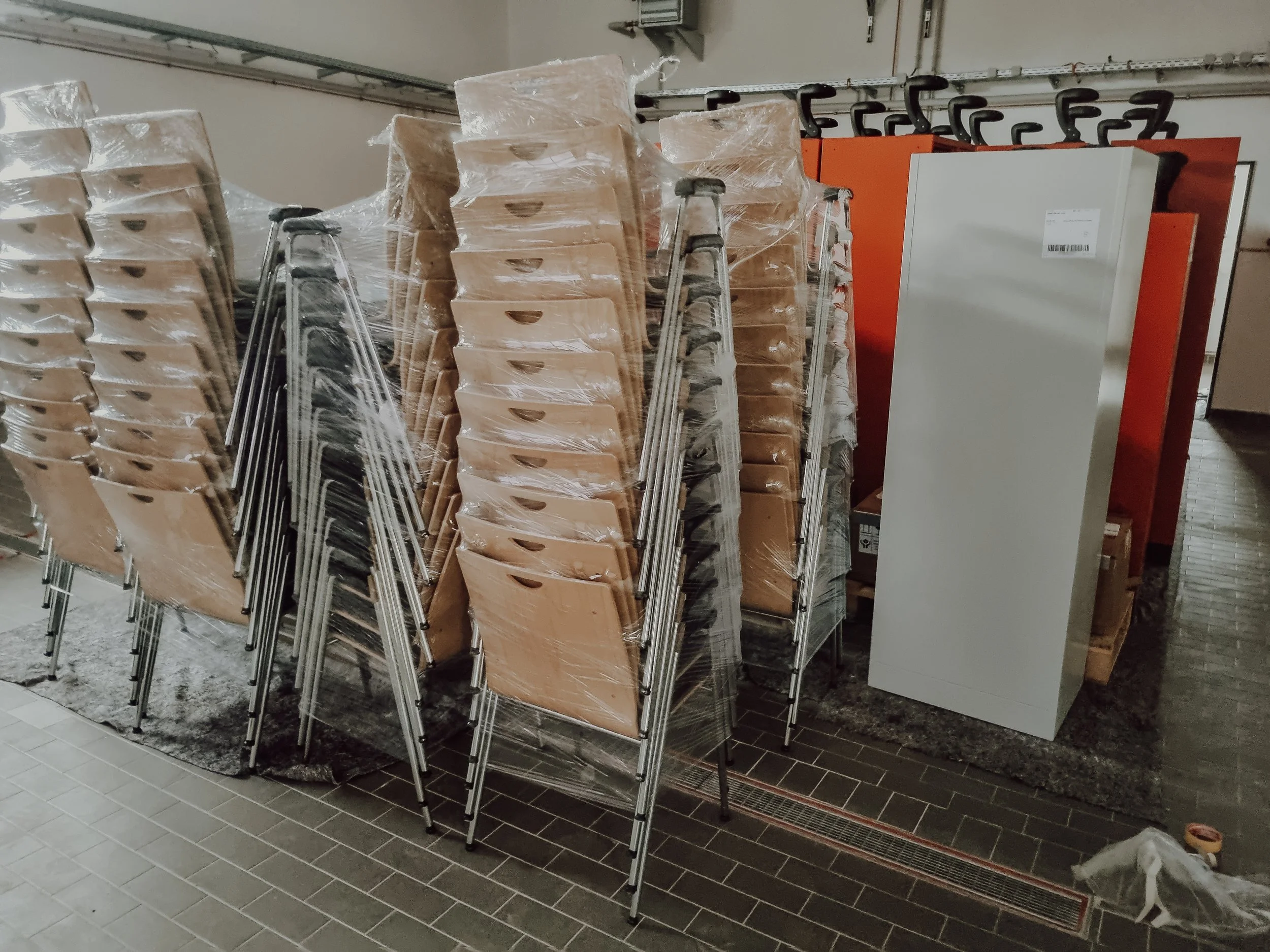 Vier Rollwagen sind mit Holzscheiten und anderen Gegenständen bedeckt, die mit Plastiktüten verpackt sind, stehen in einem Hausflur