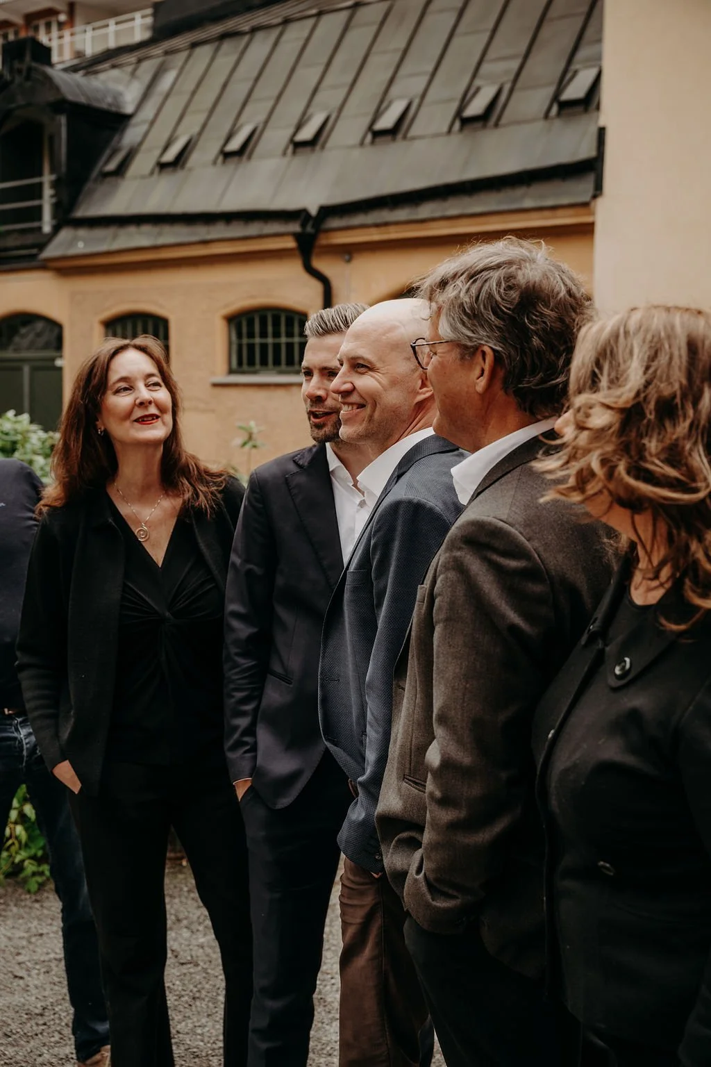 Time People Groups ledningsgrupp, samtalar utomhus framför ett gammalt byggnad med halvt rutschande tak.