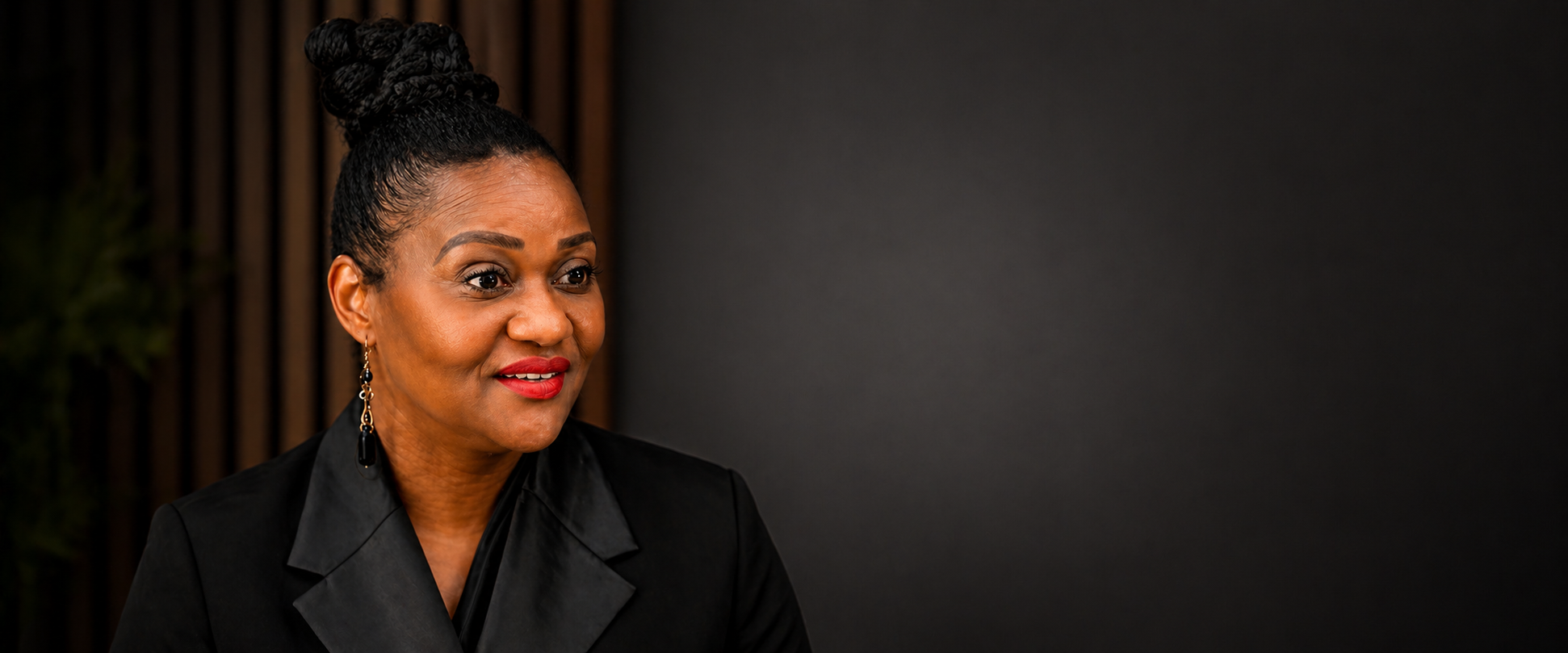 Tchiyiwe Chihana, broadcaster and moderator seated in a black blazer against a dark background