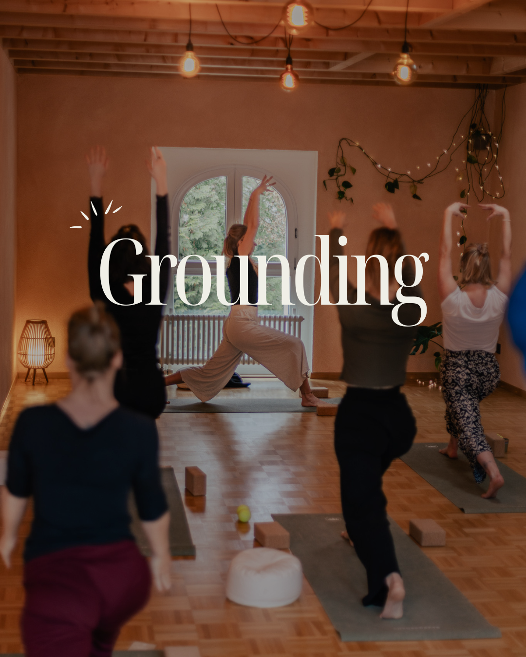 Menschen beim Yoga in einem ruhigen, lichtdurchfluteten Raum, mit der Aufschrift 'Grounding' im Vordergrund. Stressabbau, Release, Somatic Yoga Bern.