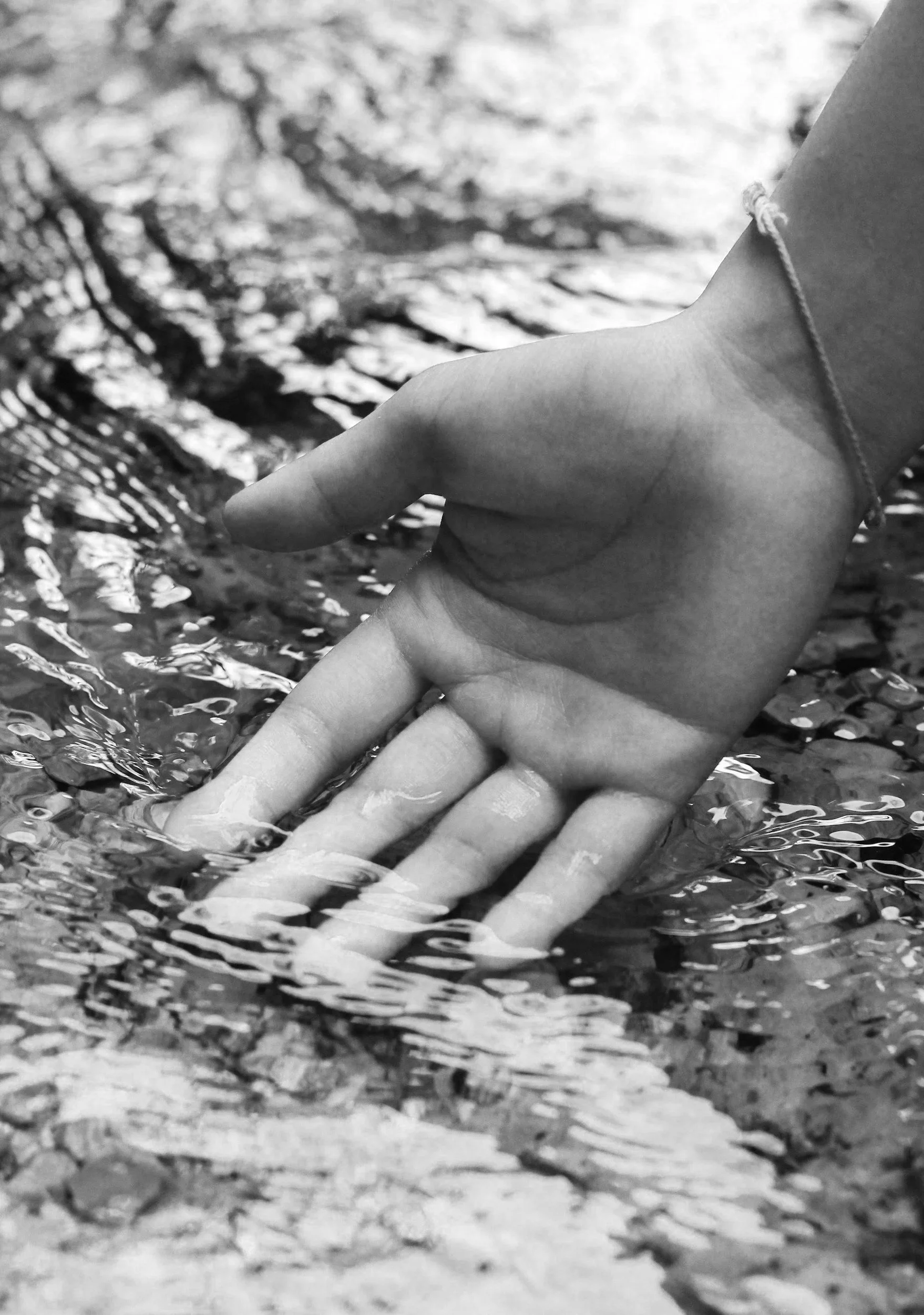 Nahaufnahme einer Hand, die sich im Wasser eines Flusses oder Bachs befindet. Körperwahrnehmung und fühlen, lebendig sein.