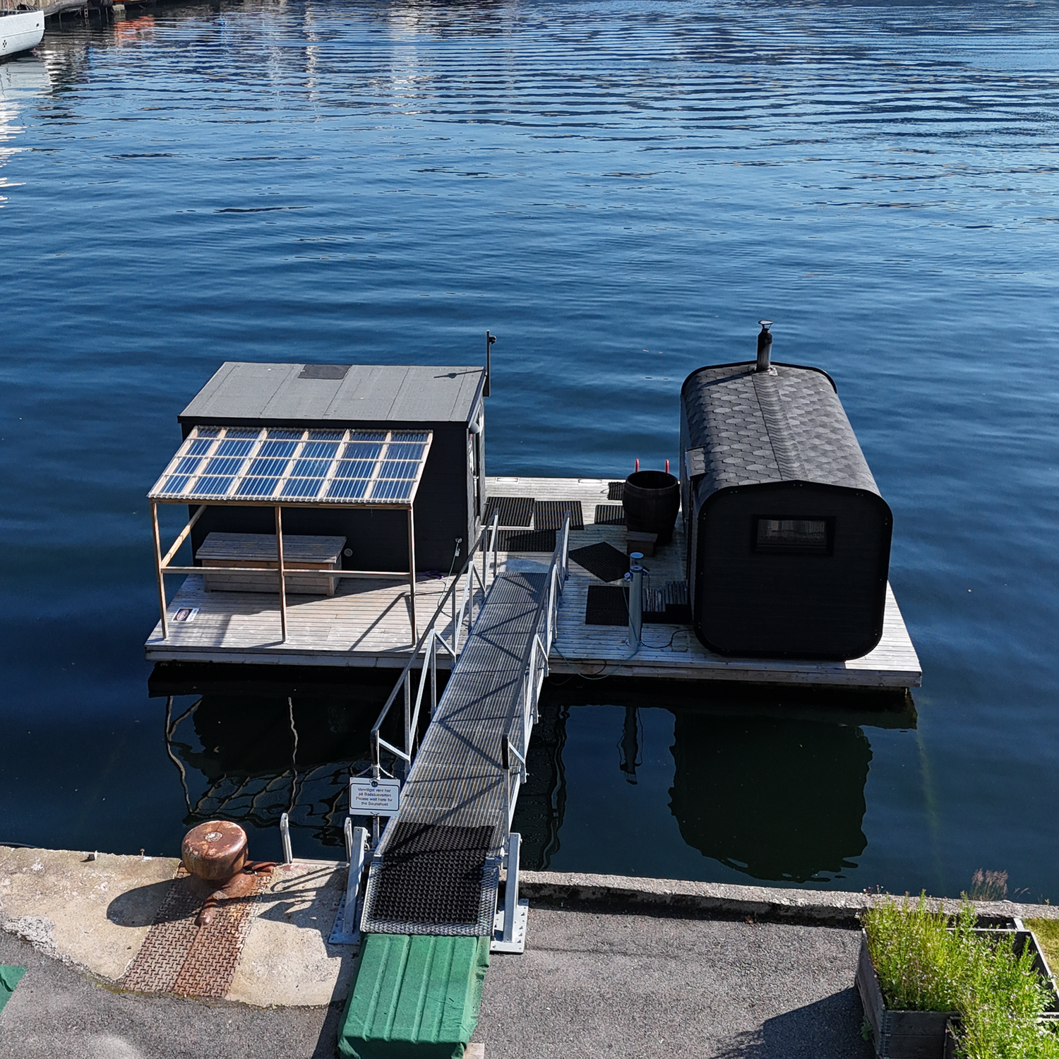 Two Heit sauna cabins on a floating platform surrounded by deep blue water.