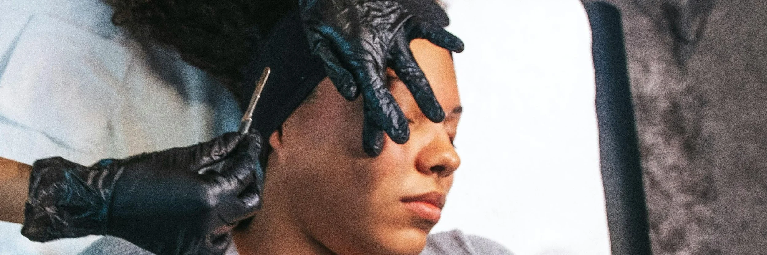 A woman with closed eyes receiving a dermaplaning on her face.