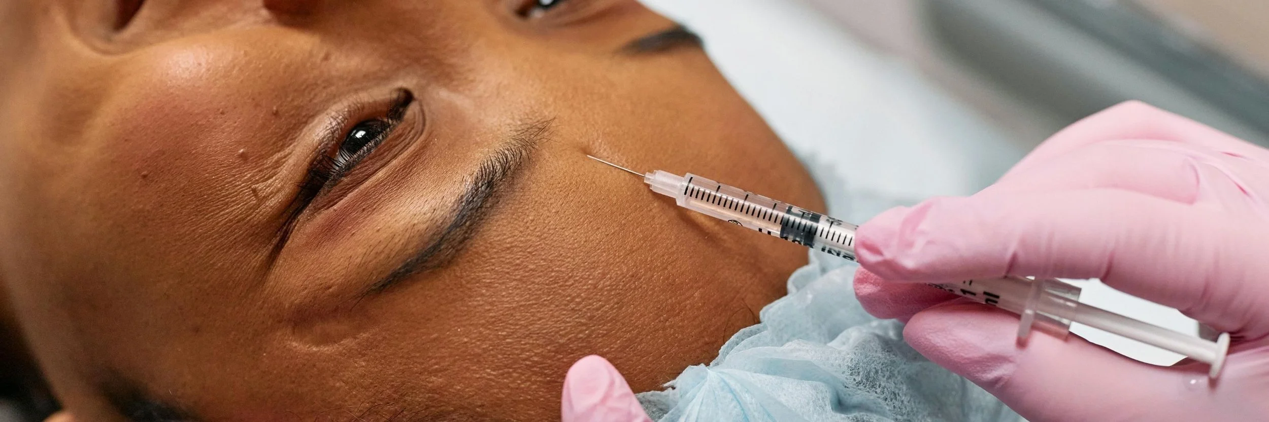 Person receiving facial injection to help with fine lines on forehead