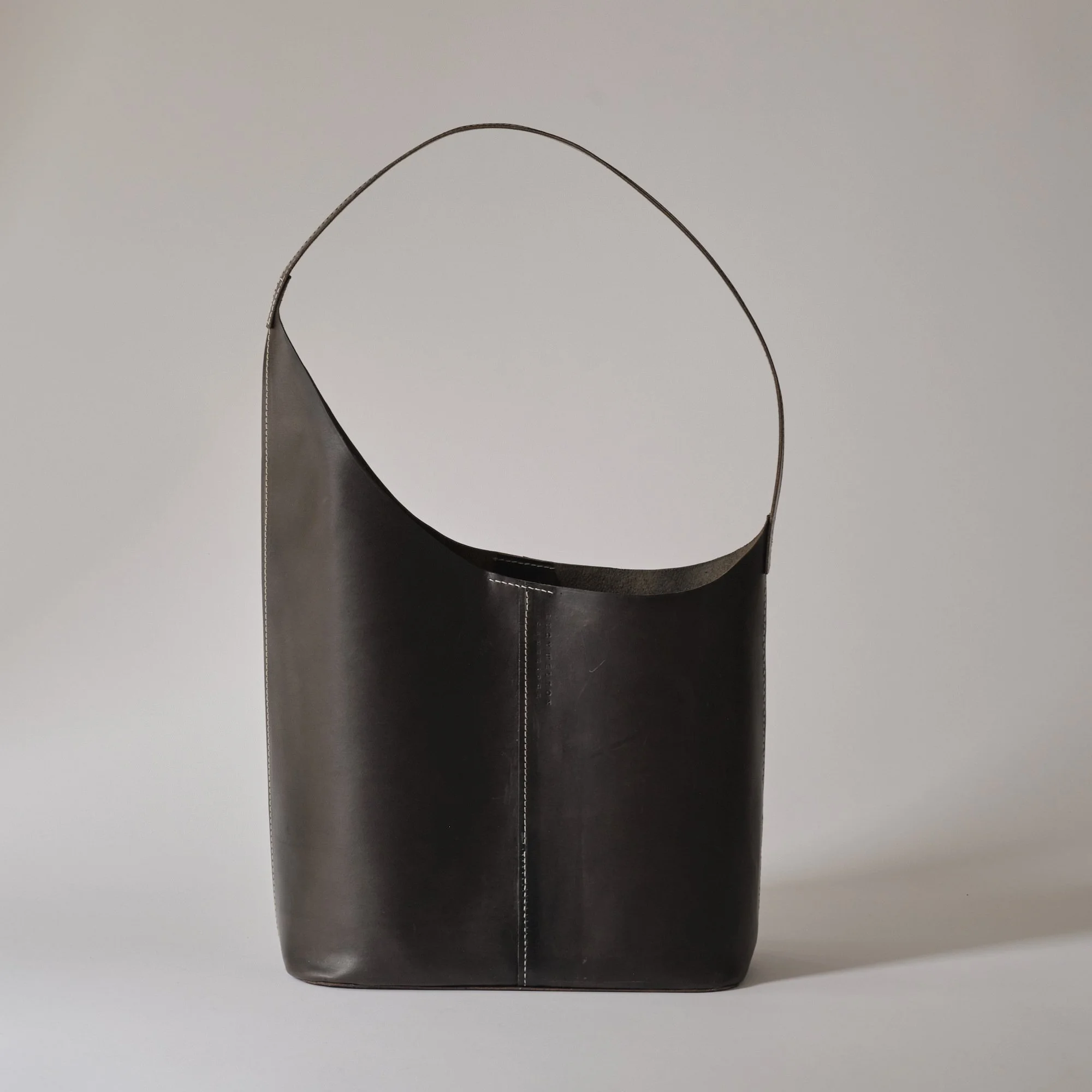 Black leather handbag with a curved strap against a plain background.
