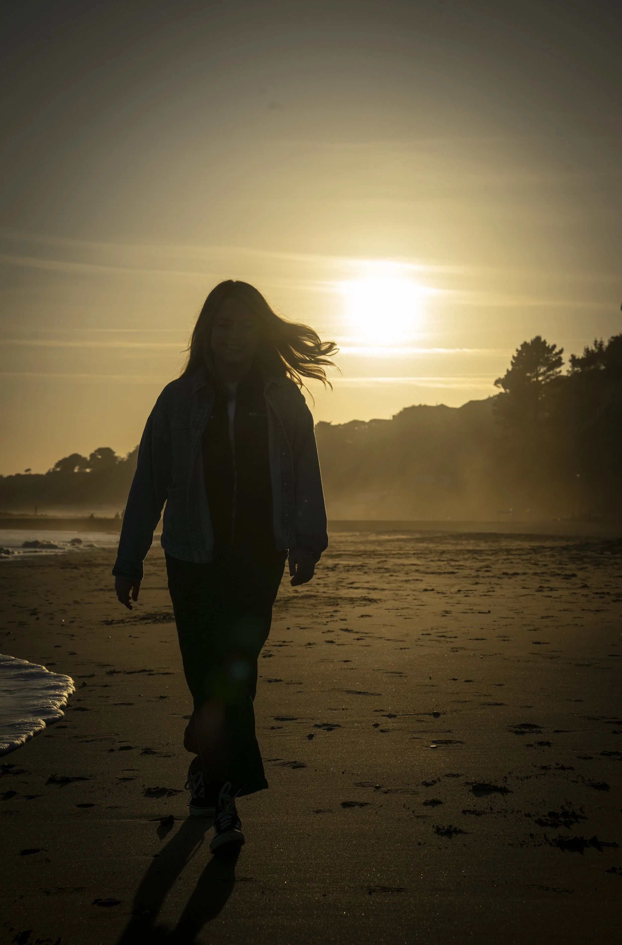 Silhouette of coach and consultant Nicola Fuller walking on the beach at sunset.