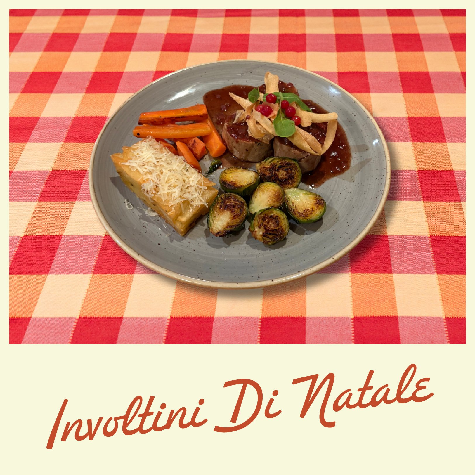 A bowl of pumpkin soup topped with croutons, pumpkin seeds, and herbs on a red and orange checkered tablecloth.