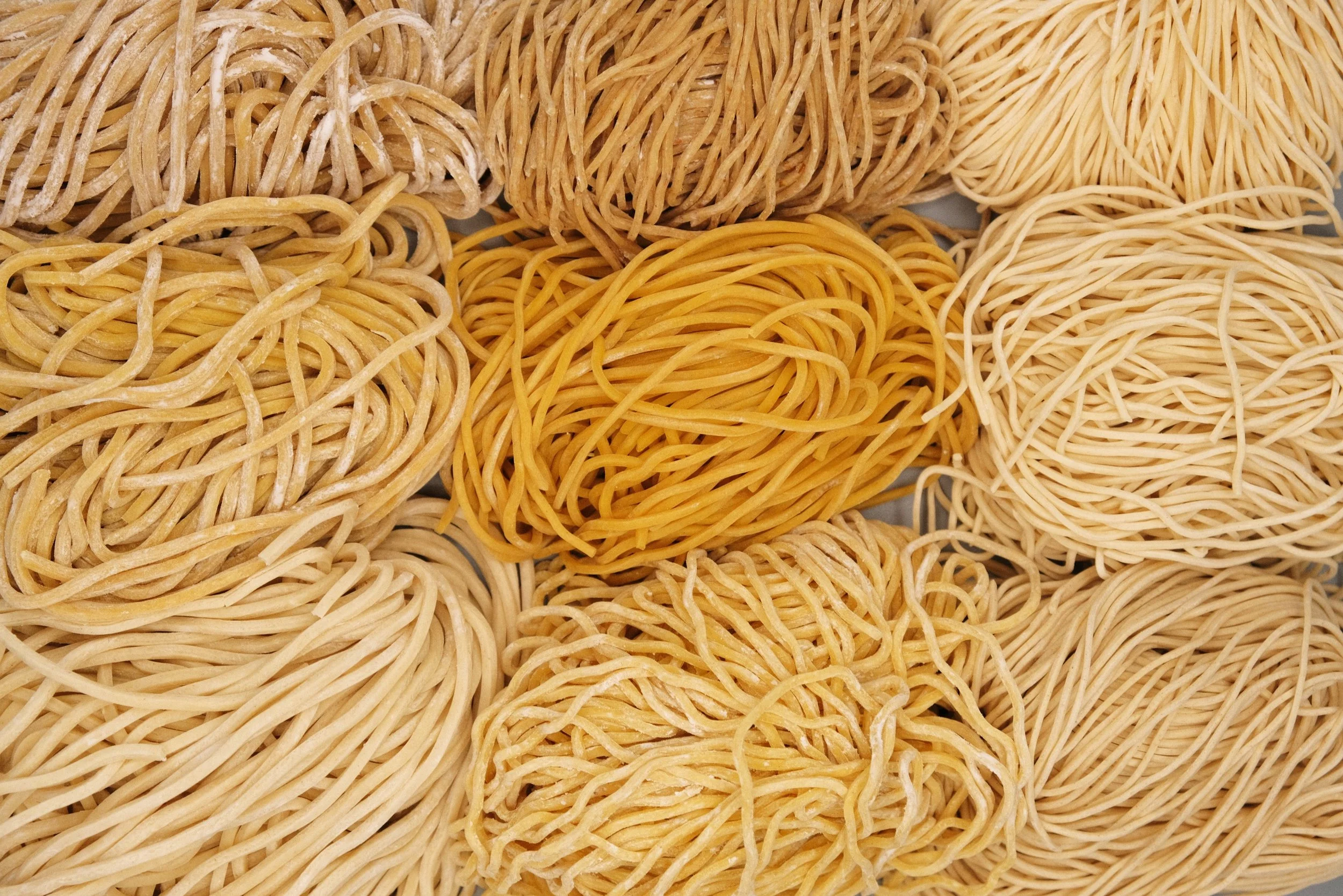 Various types of uncooked Chinese, Taiwanese and Cantonese noodles arranged together.