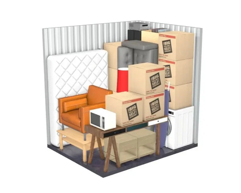 A storage unit filled with furniture and household items, including a mattress, sofa, microwave, stacked boxes, lamp, washing machine, and cleaning supplies.
