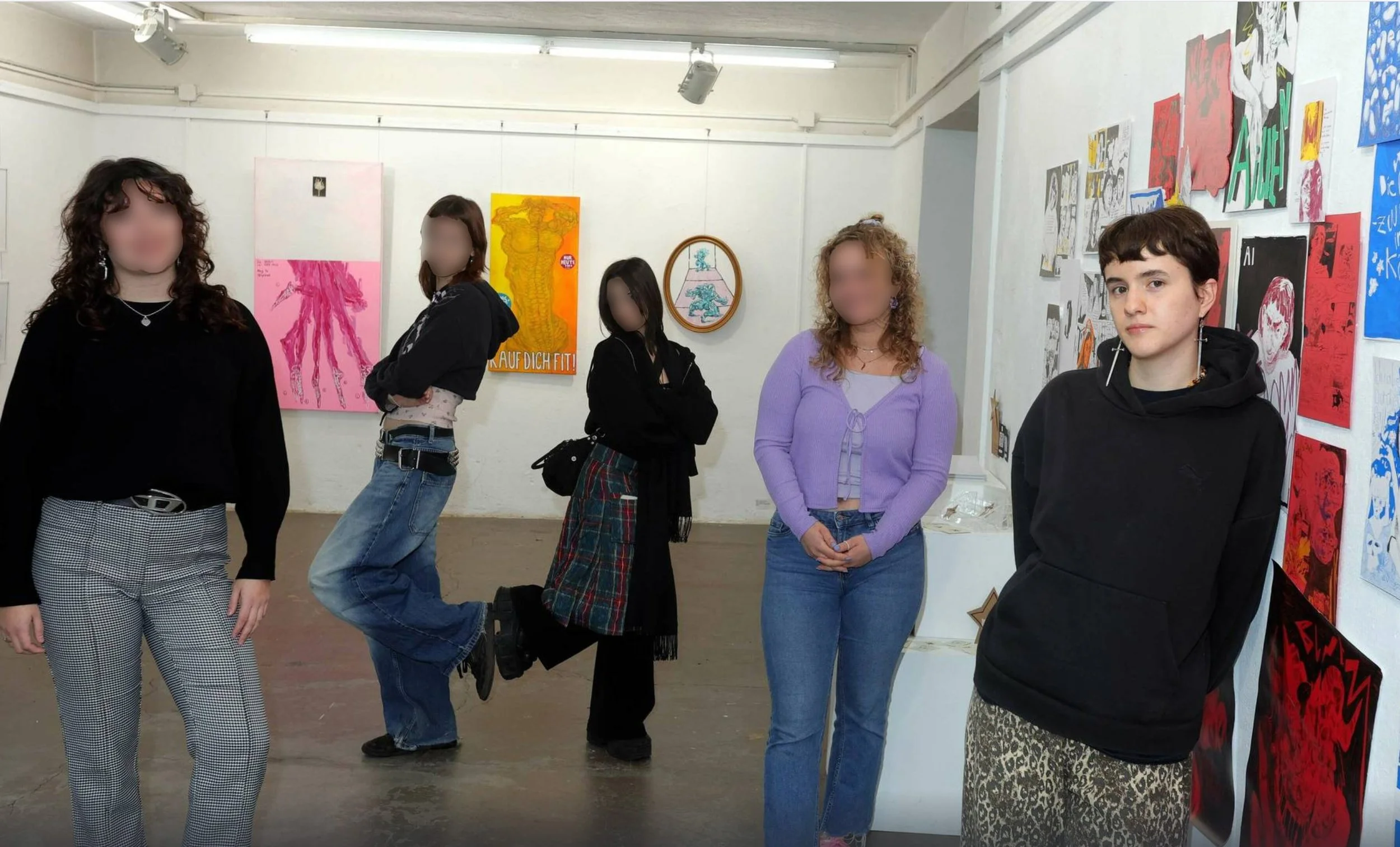 Fünf junge Menschen stehen in einer Kunstgalerie vor einem weißen Wand mit Kunstwerken in bunten Farben. Sie tragen casual Kleidung und schauen in unterschiedliche Richtungen.