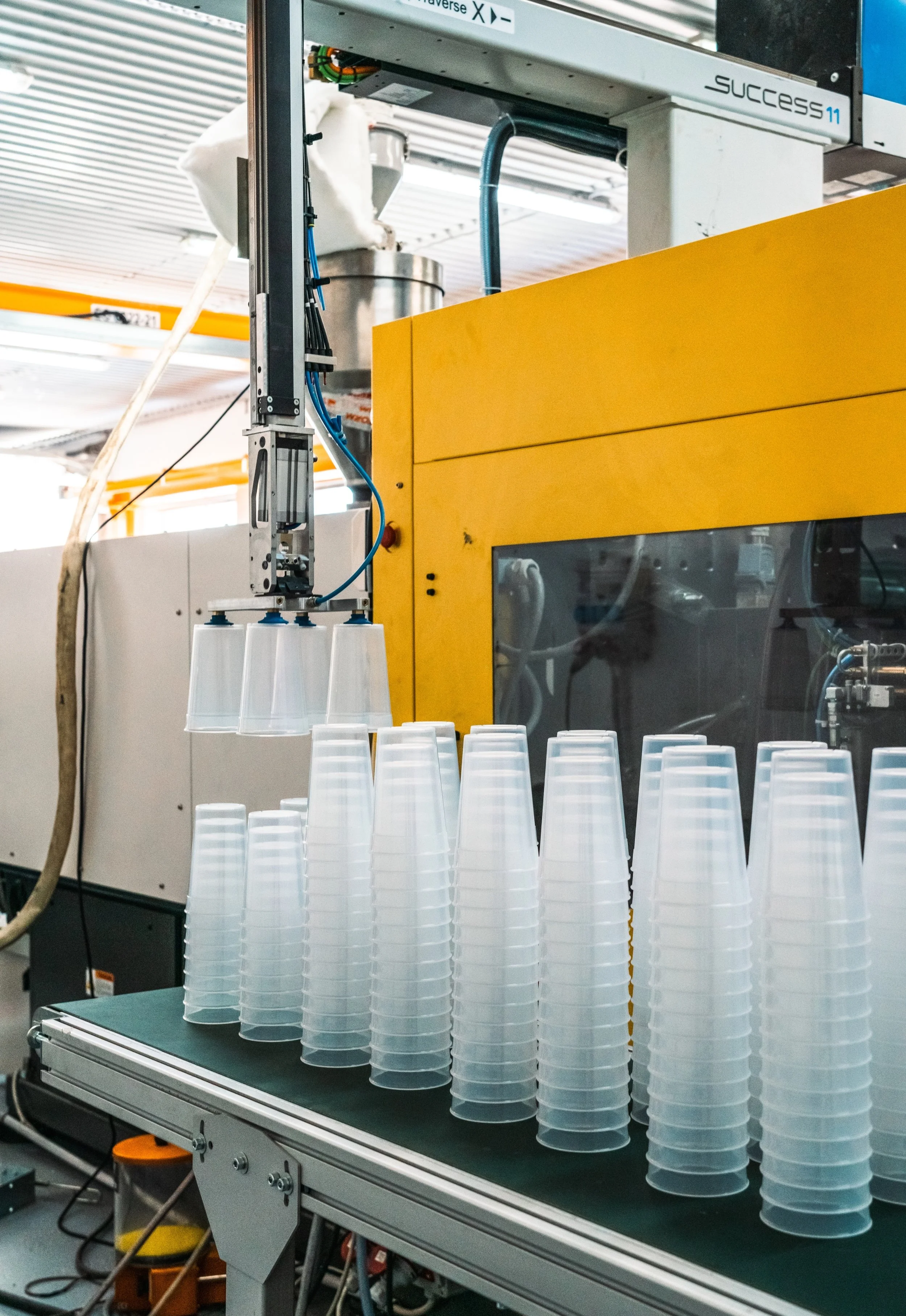 Plastic cups stacked upside down on a conveyor belt in a manufacturing or packaging facility.