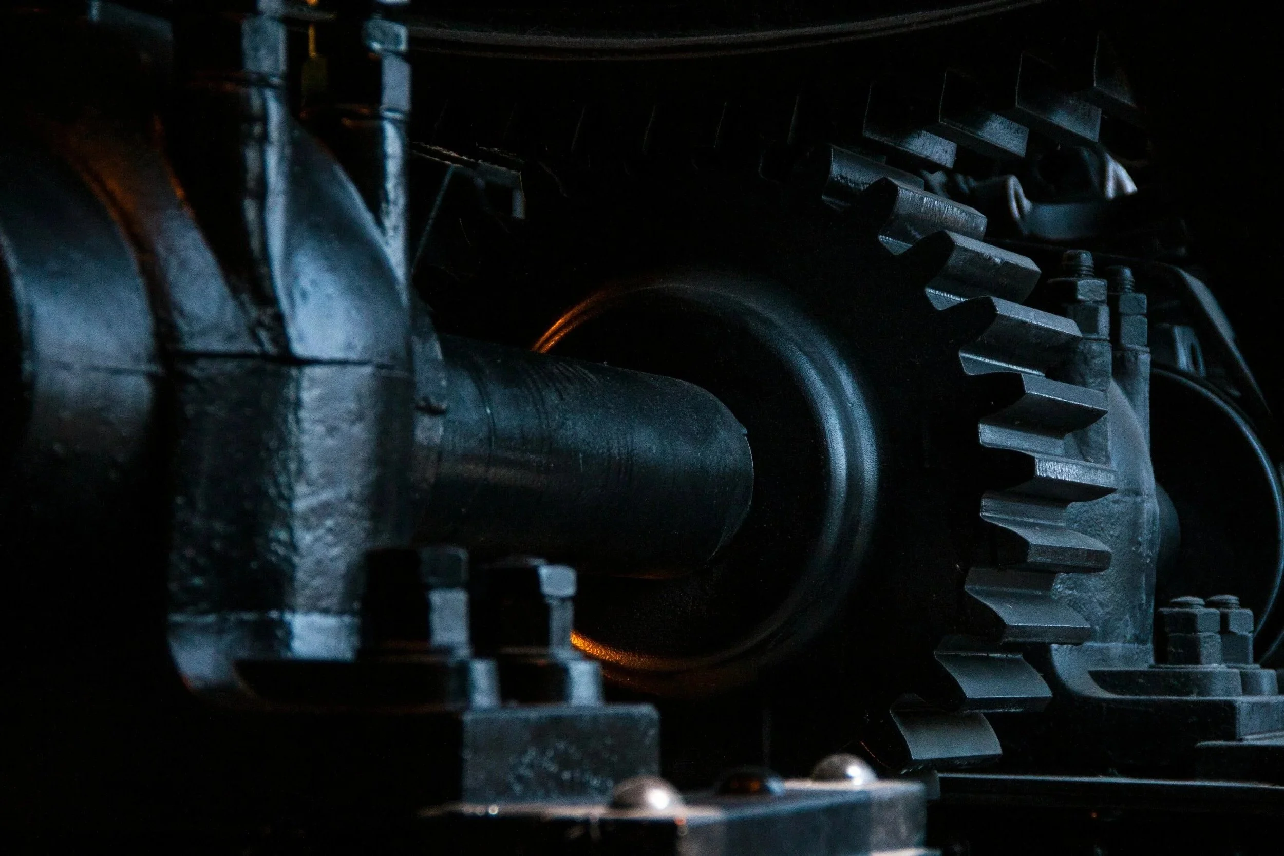 Close-up of a large industrial gear and axle with dark mechanical components.