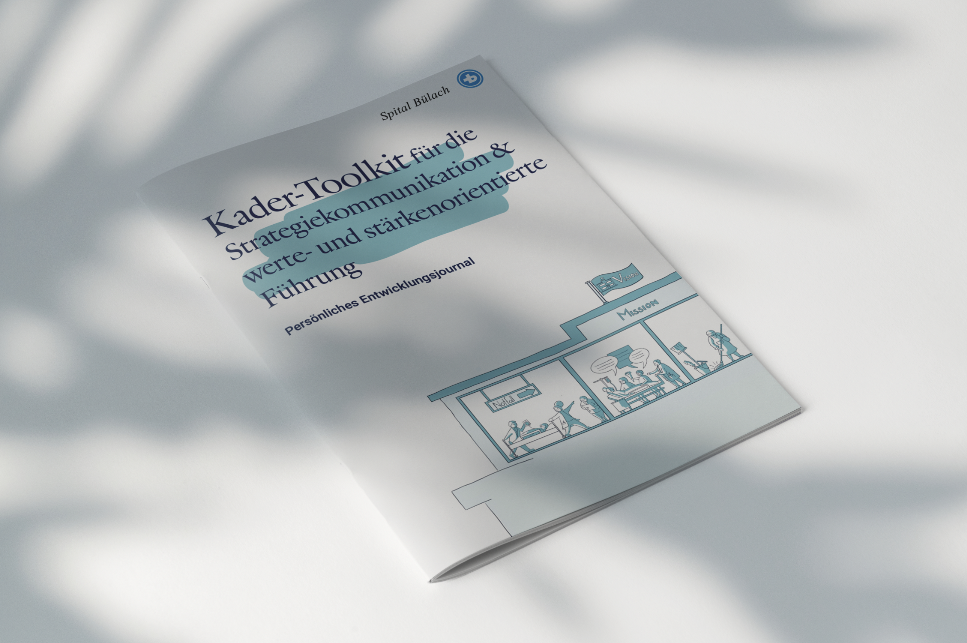 Ein gedruckte Broschuere für das Spital Buelach mit dem Titel "Kader-Toolkit für die Strategiekommunikation & Werte- und stärkenorientierte Führung" liegt auf einem weißen Stoffhintergrund, mit einer Illustration eines Gebäudes auf der Titelseite.