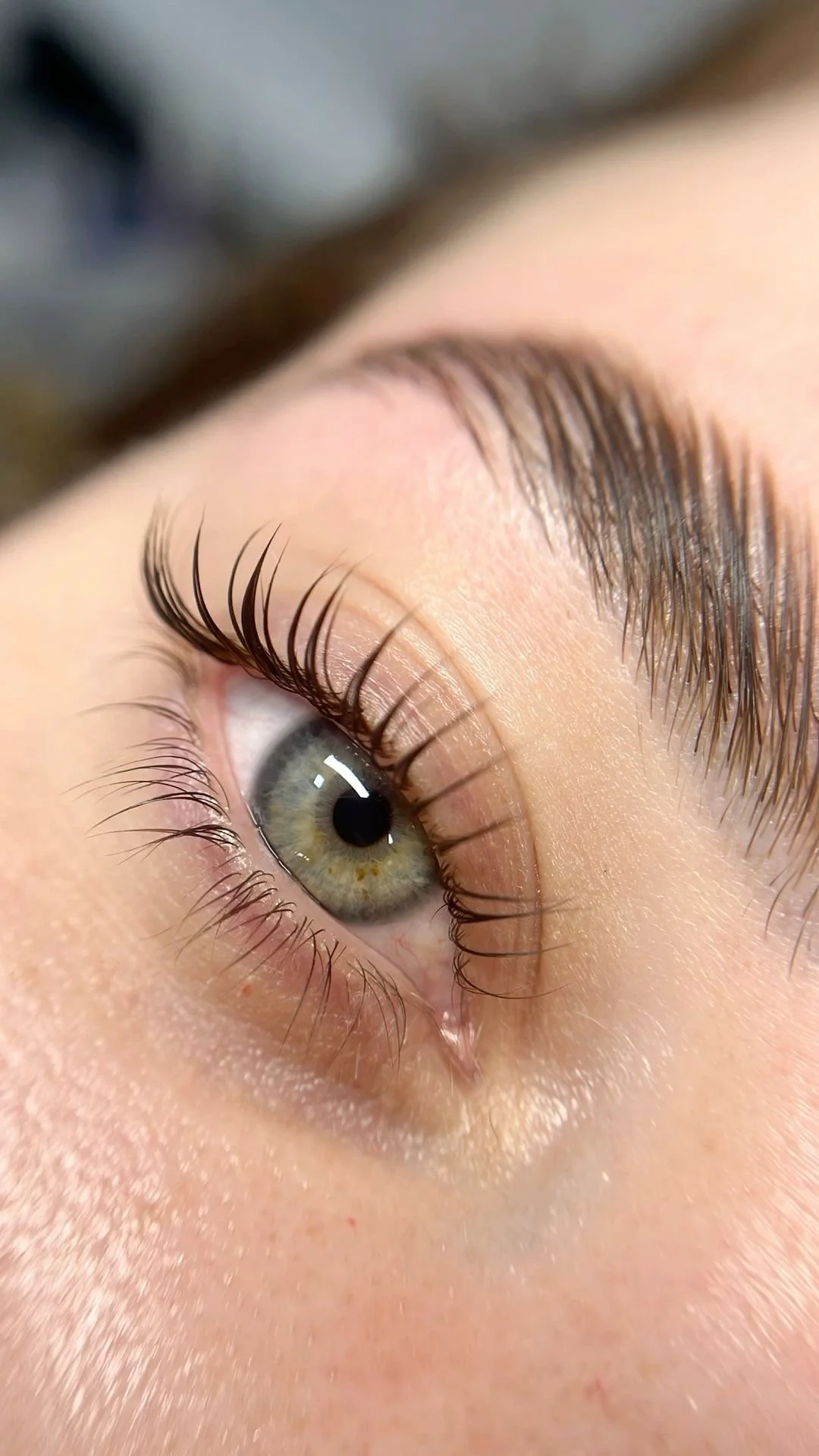 Close-up of a person's green eye, showing detailed eyelashes and skin texture.