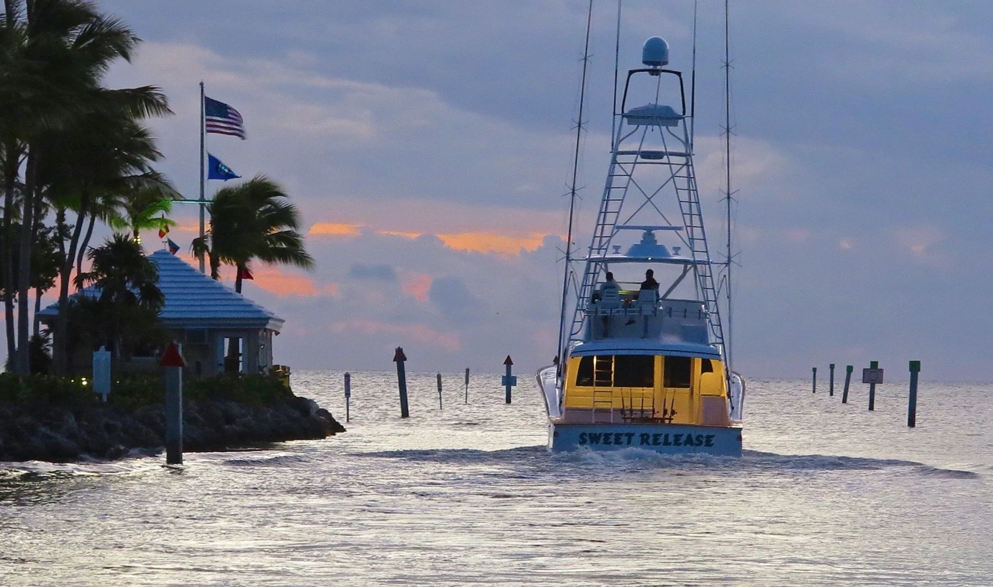 A sportfishing boat named 'Sweet Release' sailing away from Ocean Reef Club at sunrise.