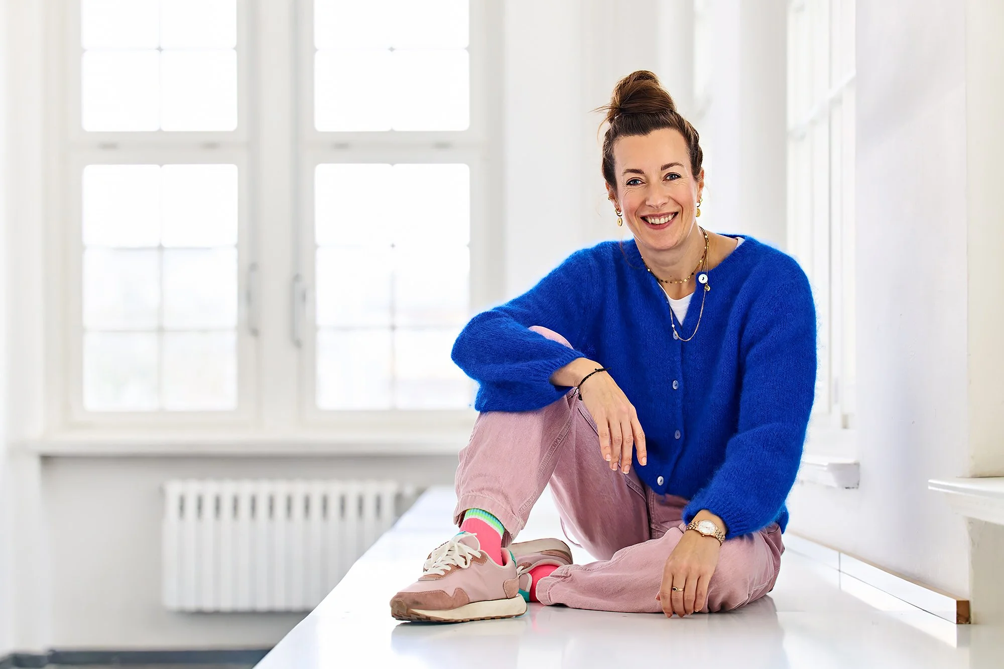 Maria Weding mit blauem Pullover sitzend auf Werkbank