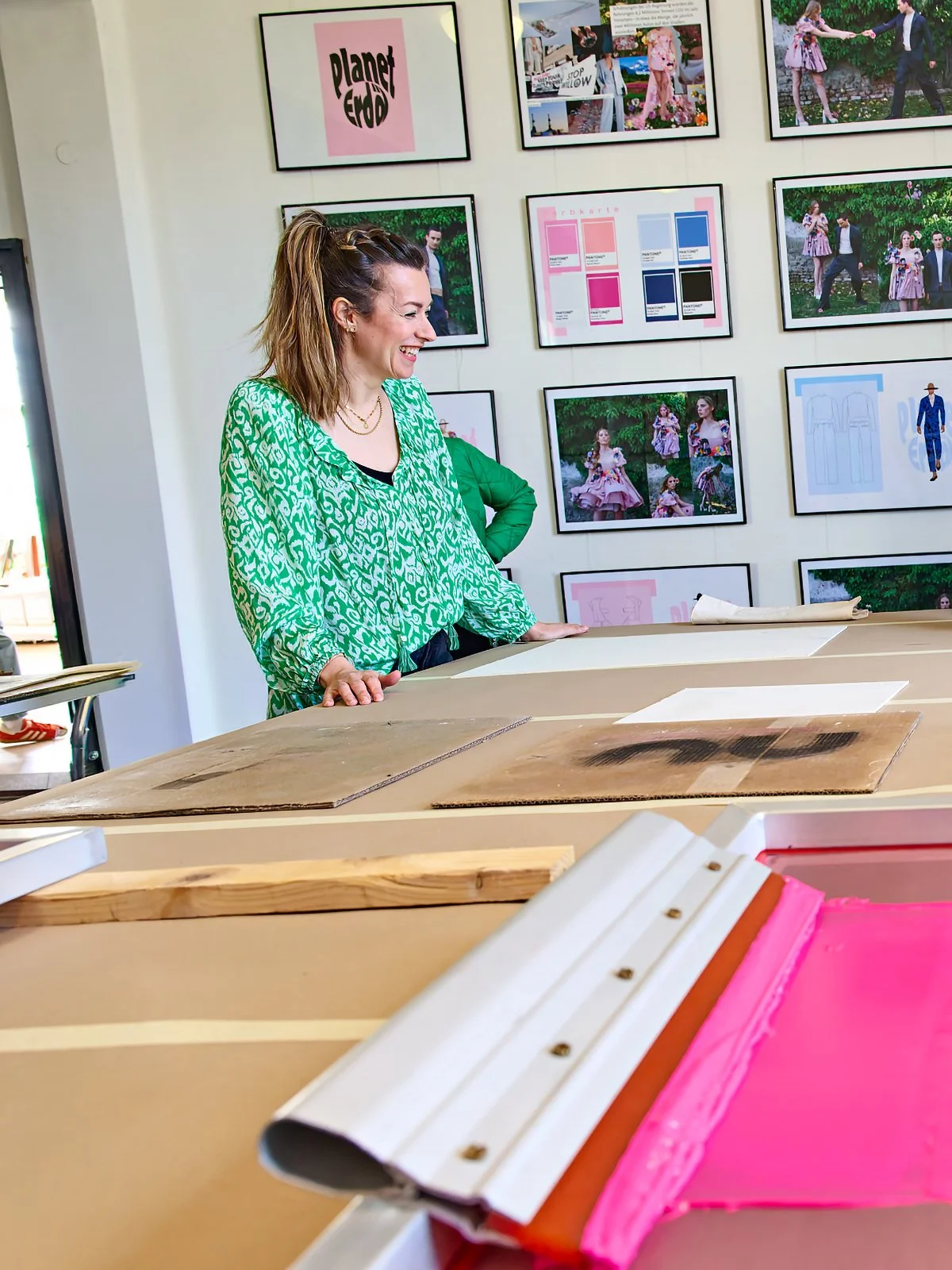 Maria Weding in einer leuchtend grünen Bluse am Zuschneidetisch der Designschule