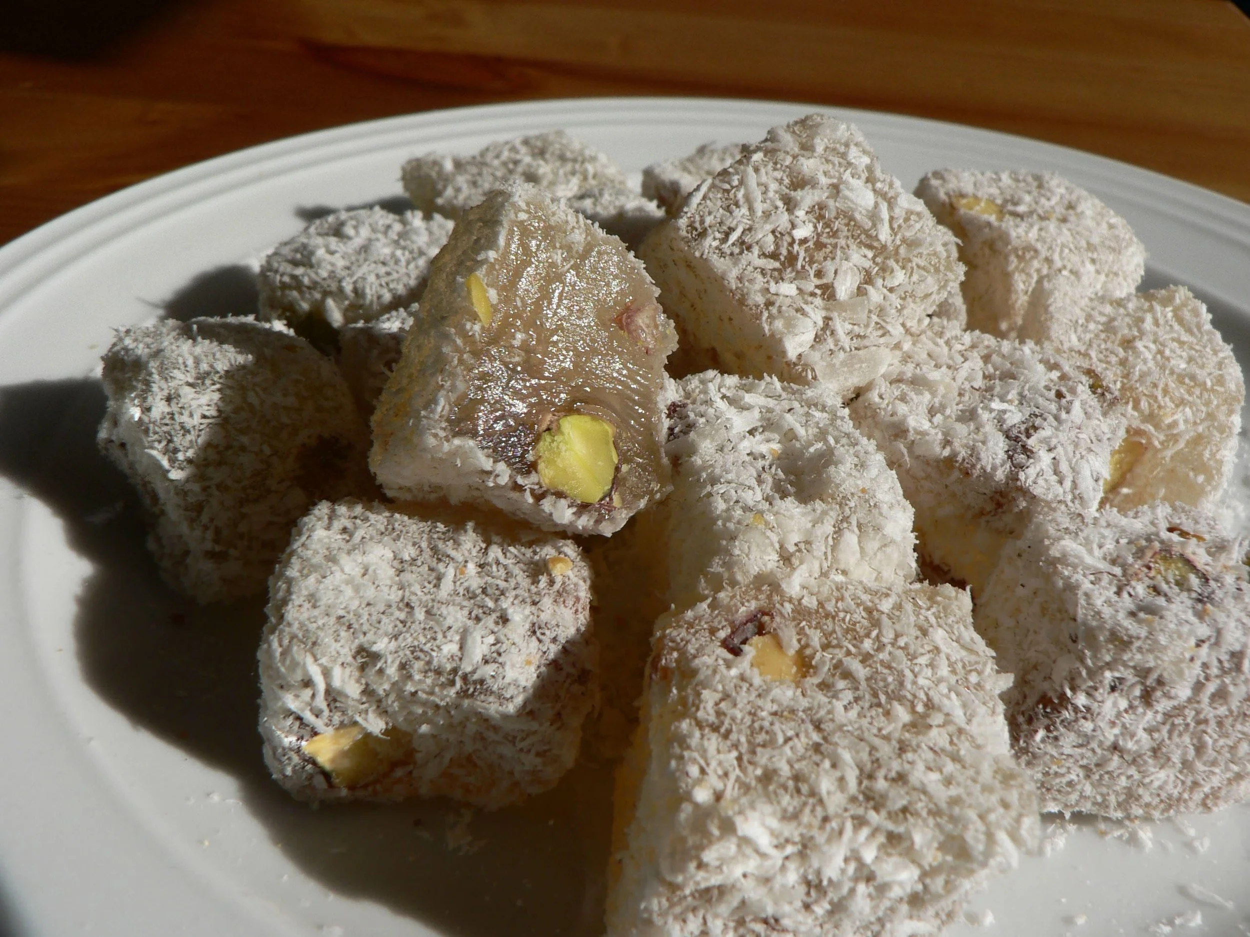 Plate of Turkish delight coated in powdered sugar, with visible nuts inside.