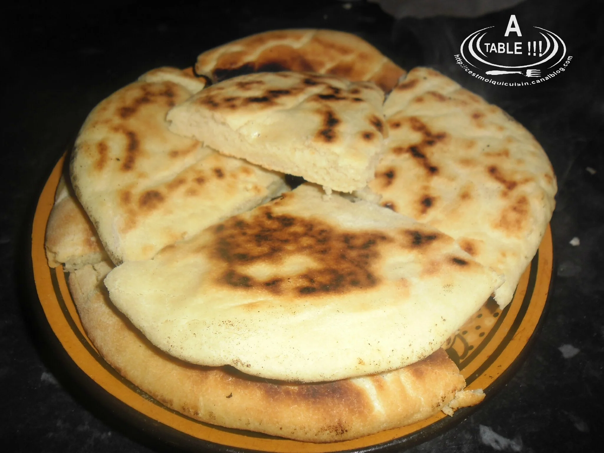 Close-up of several pieces of flatbread or naan on a yellow plate with black and orange stripes