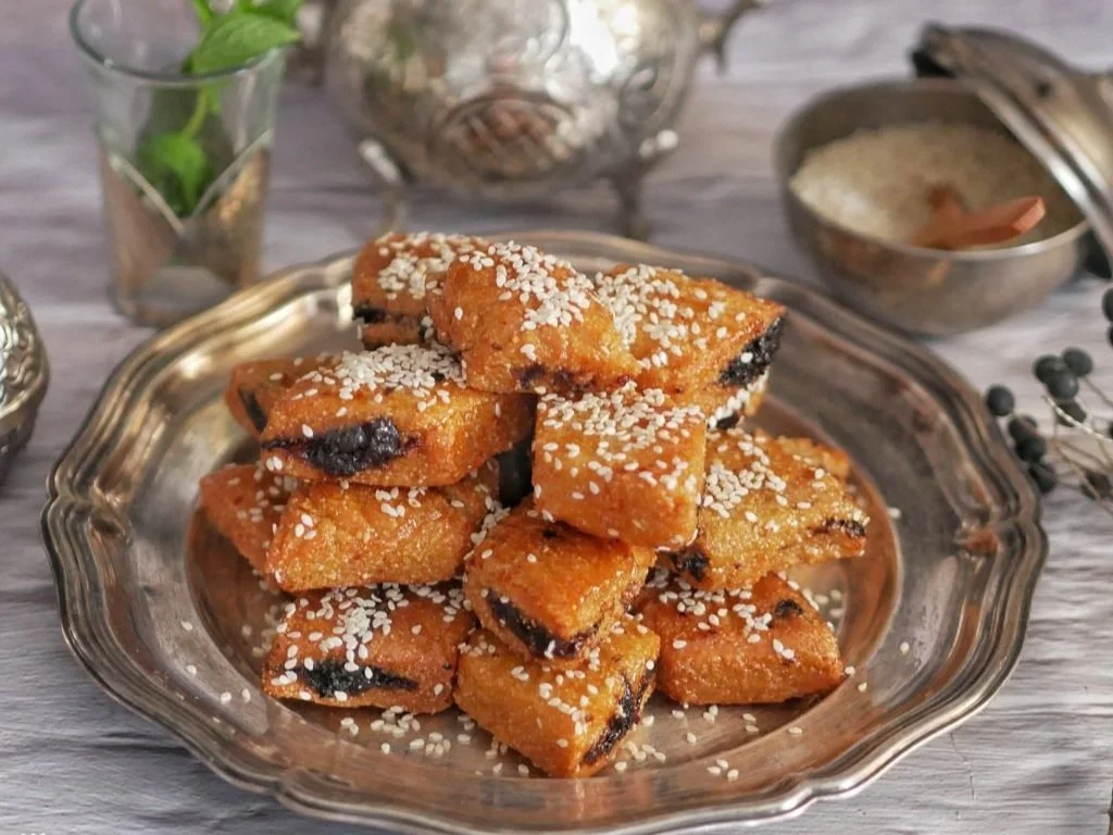 Pile of blueberry-filled lemon bars topped with sugar crystals on a glass serving dish.