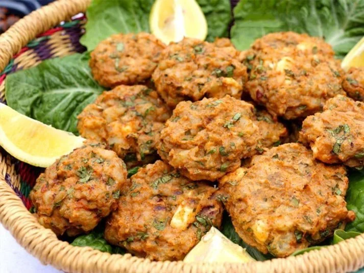 A basket of falafel balls garnished with lemon wedges and lettuce.