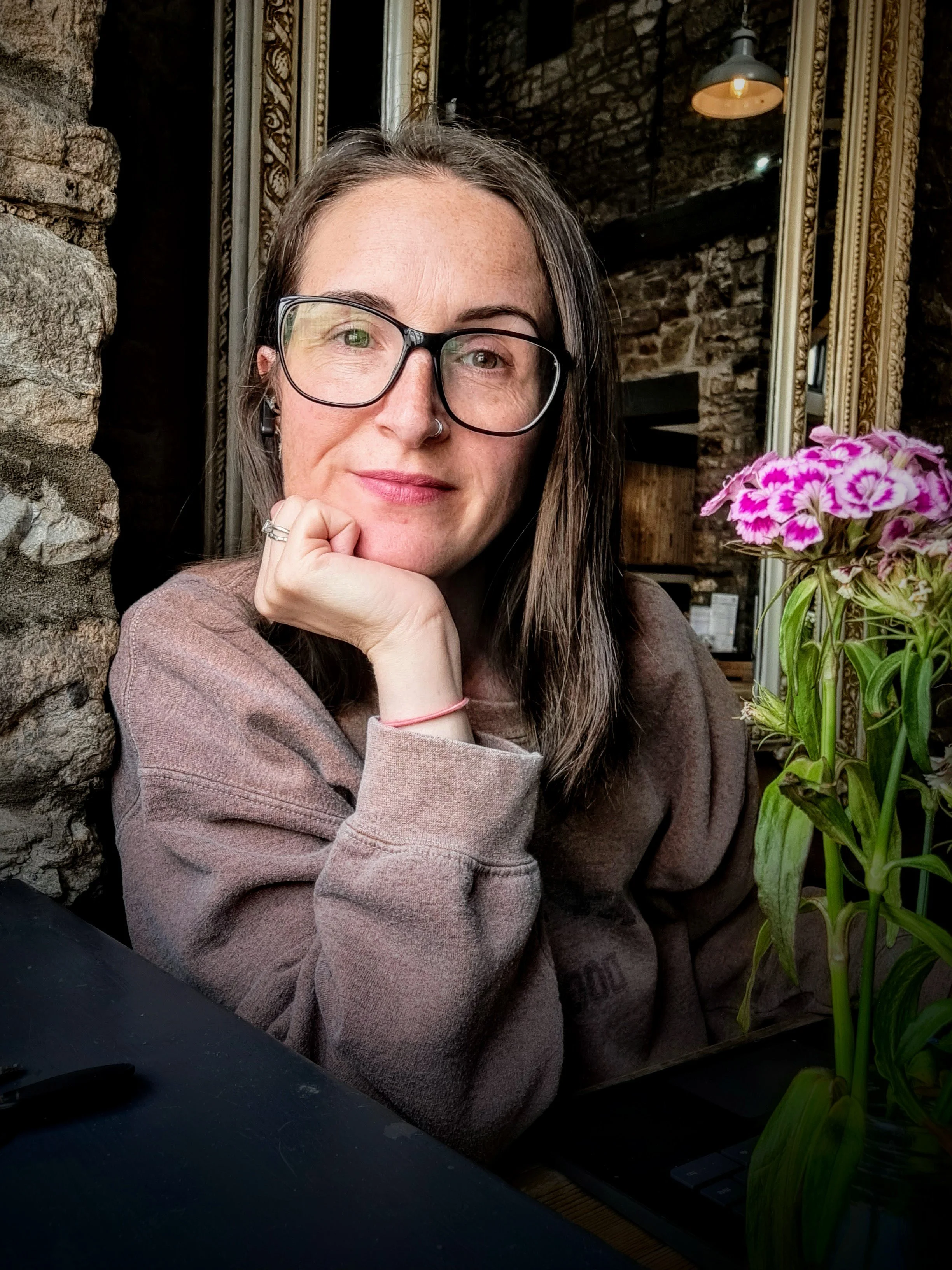 Sam, staring at the camera, smiling, chin resting in her hand