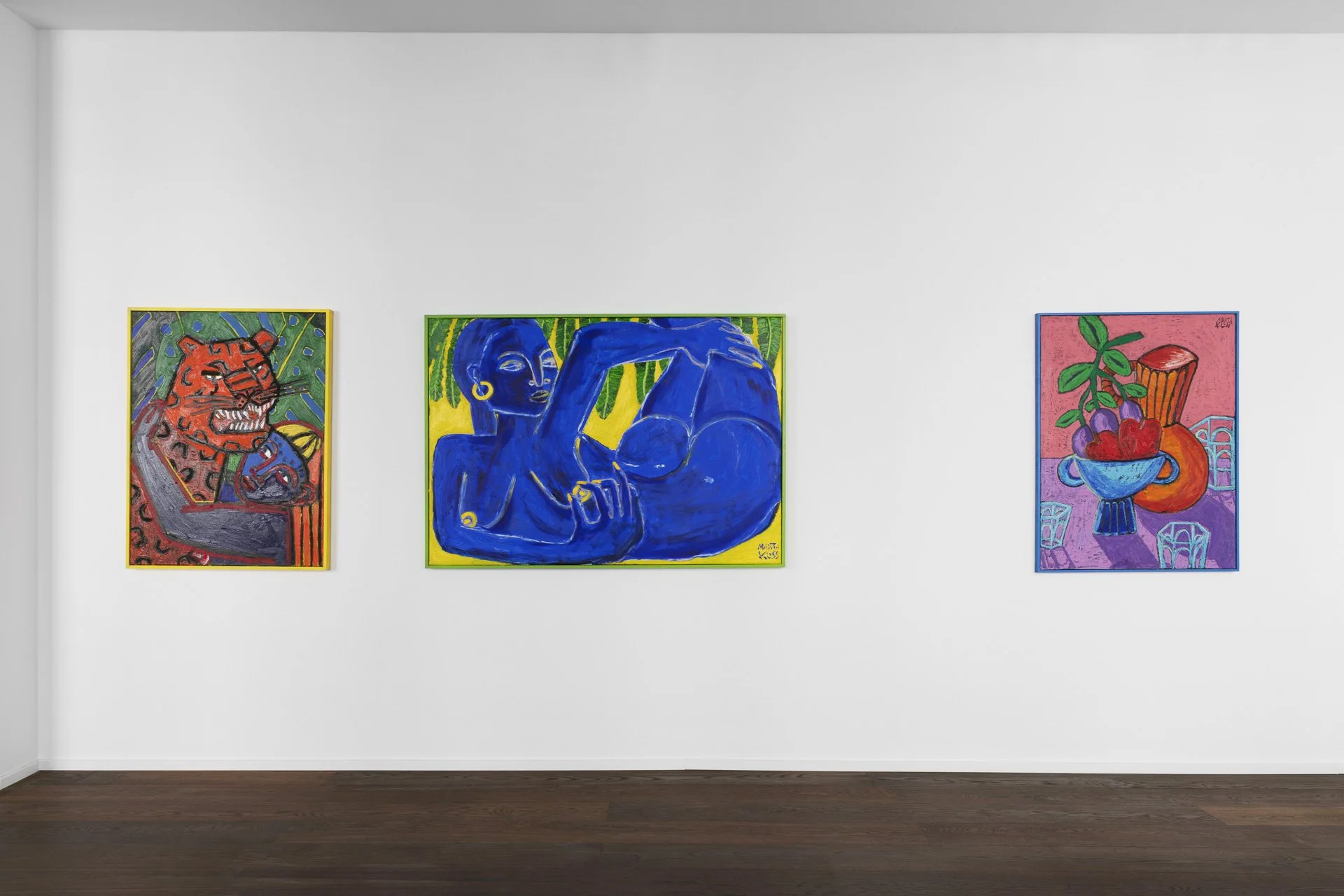Three colorful paintings hang on a white gallery wall. The left painting features a fierce tiger with dark stripes on an orange and red background. The middle painting shows a blue woman with gold hoop earrings, holding her arm across her chest, with green foliage in the background. The right painting depicts a bowl filled with cherries, grapes, and an orange, with a pink background and three ice cubes in front.