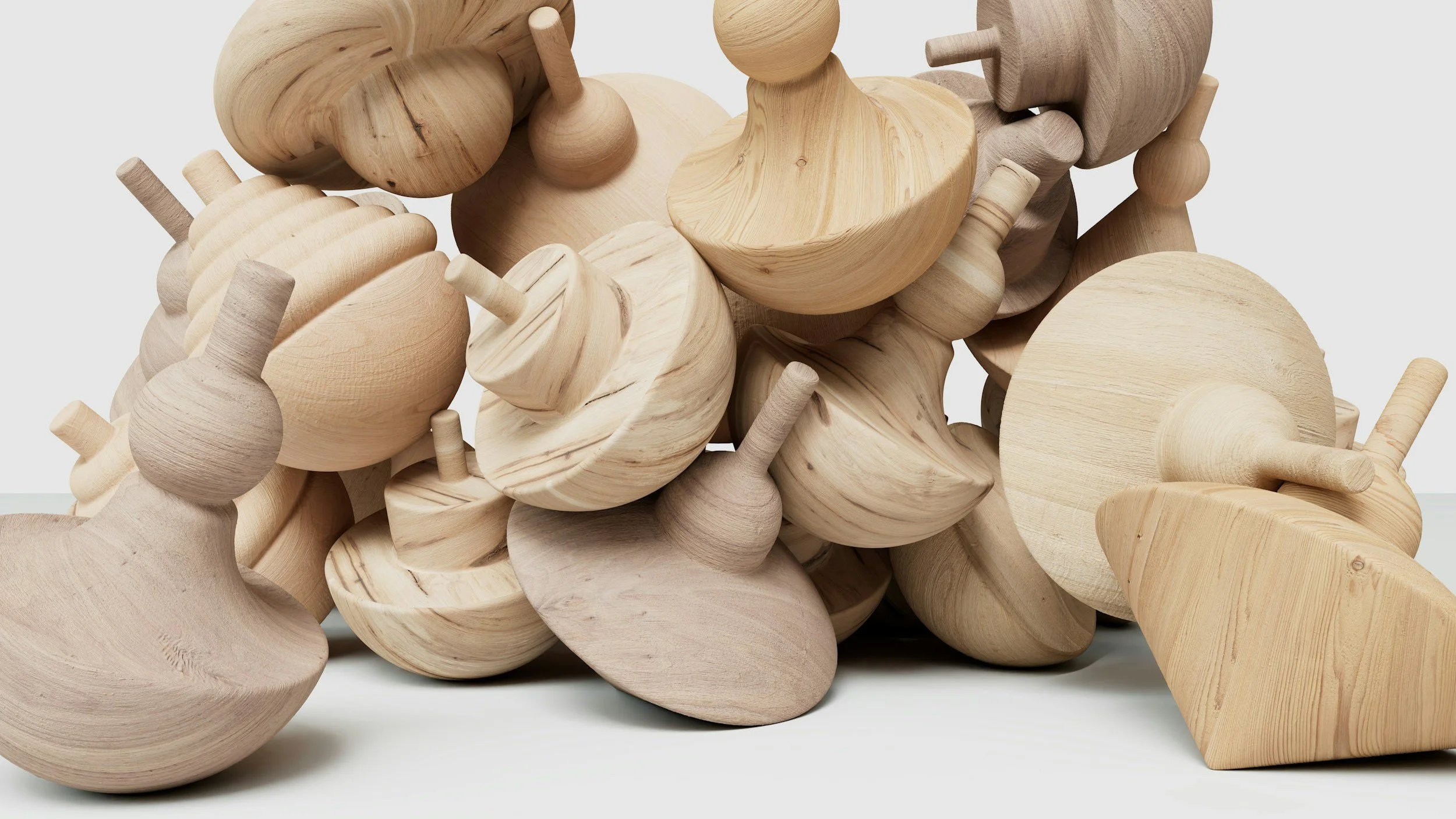 Haufen aus naturbelassenen Holzspieltüchern in verschiedenen Formen auf weißem Hintergrund.