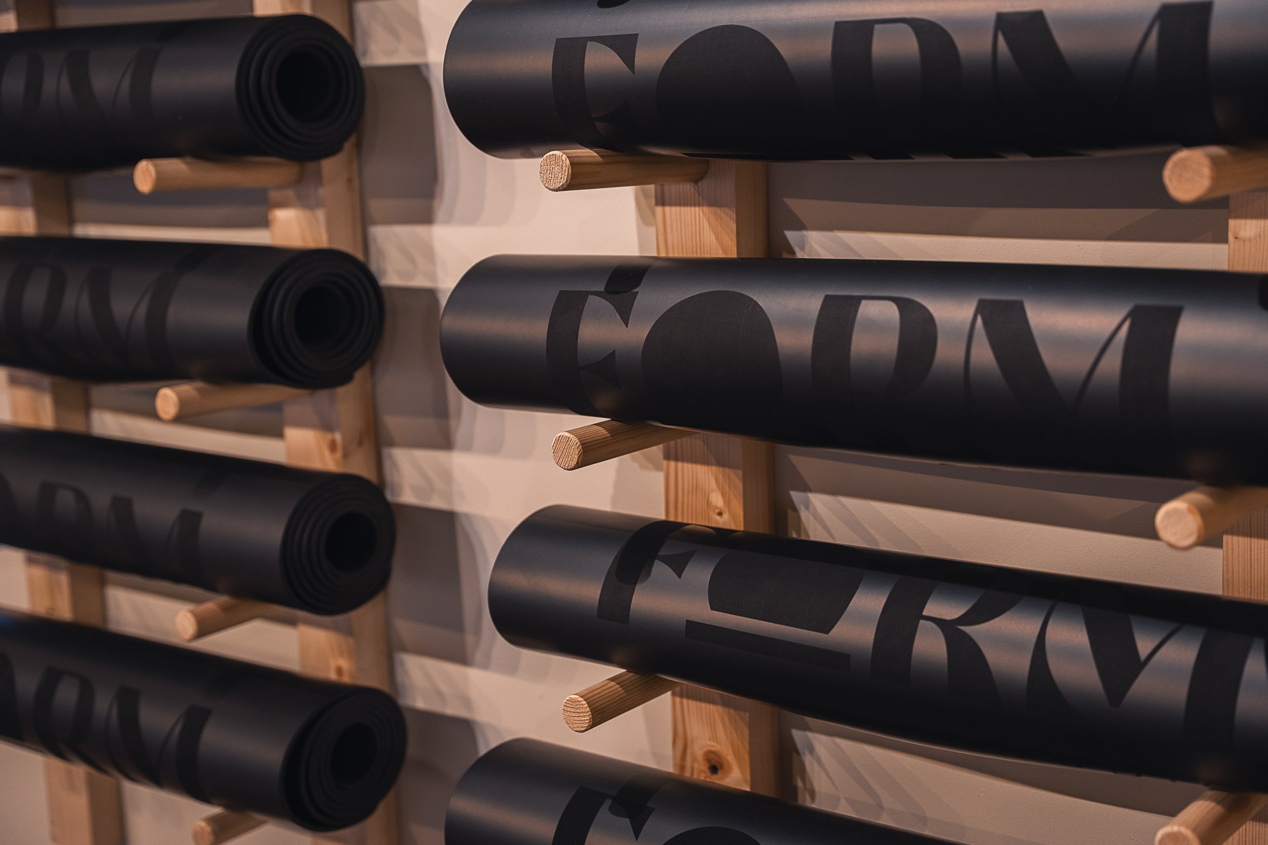 Black cylindrical rolls with printed text mounted on a wooden rack.