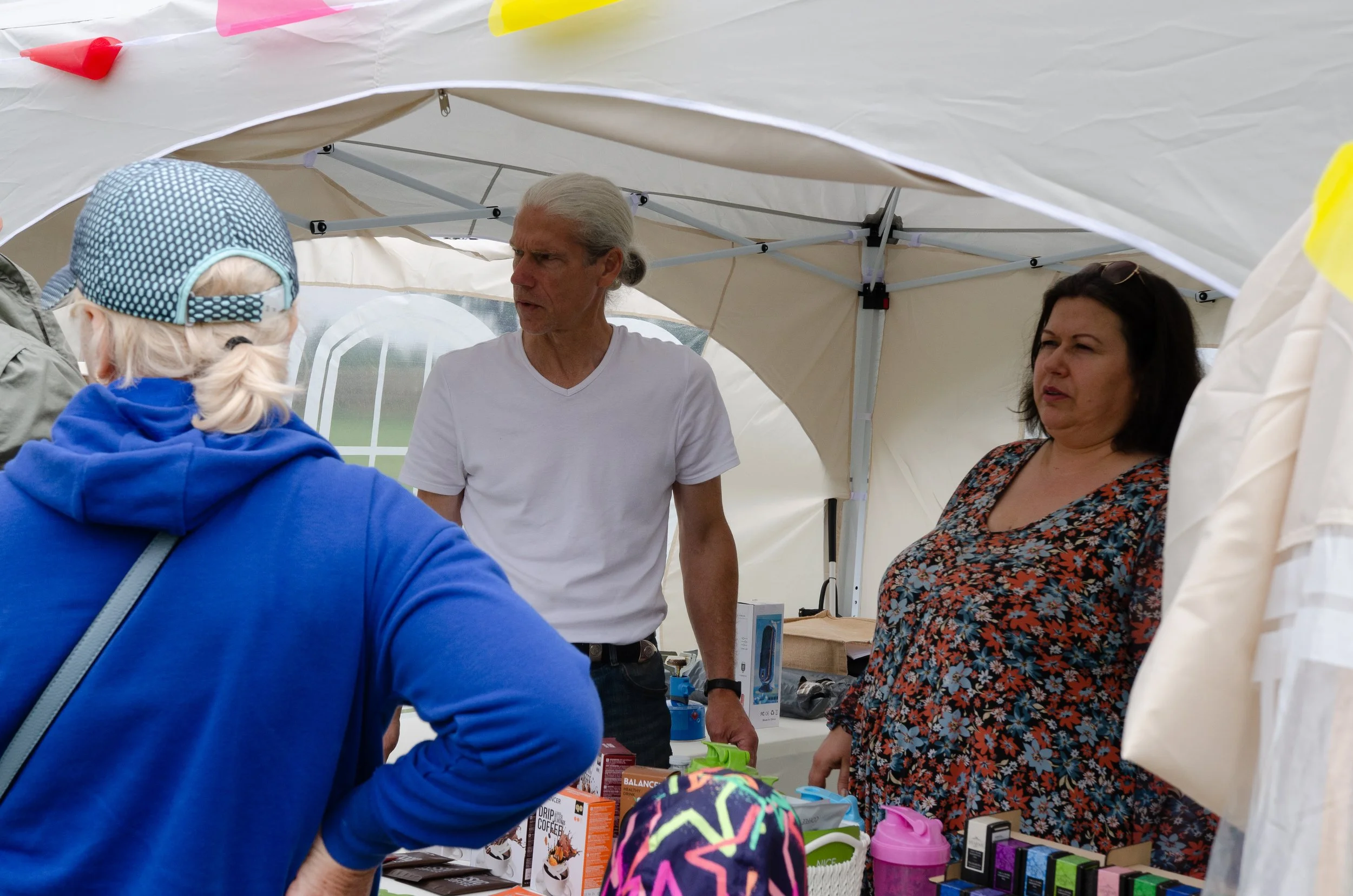 People talking inside a cream-colored tent at a market or fair