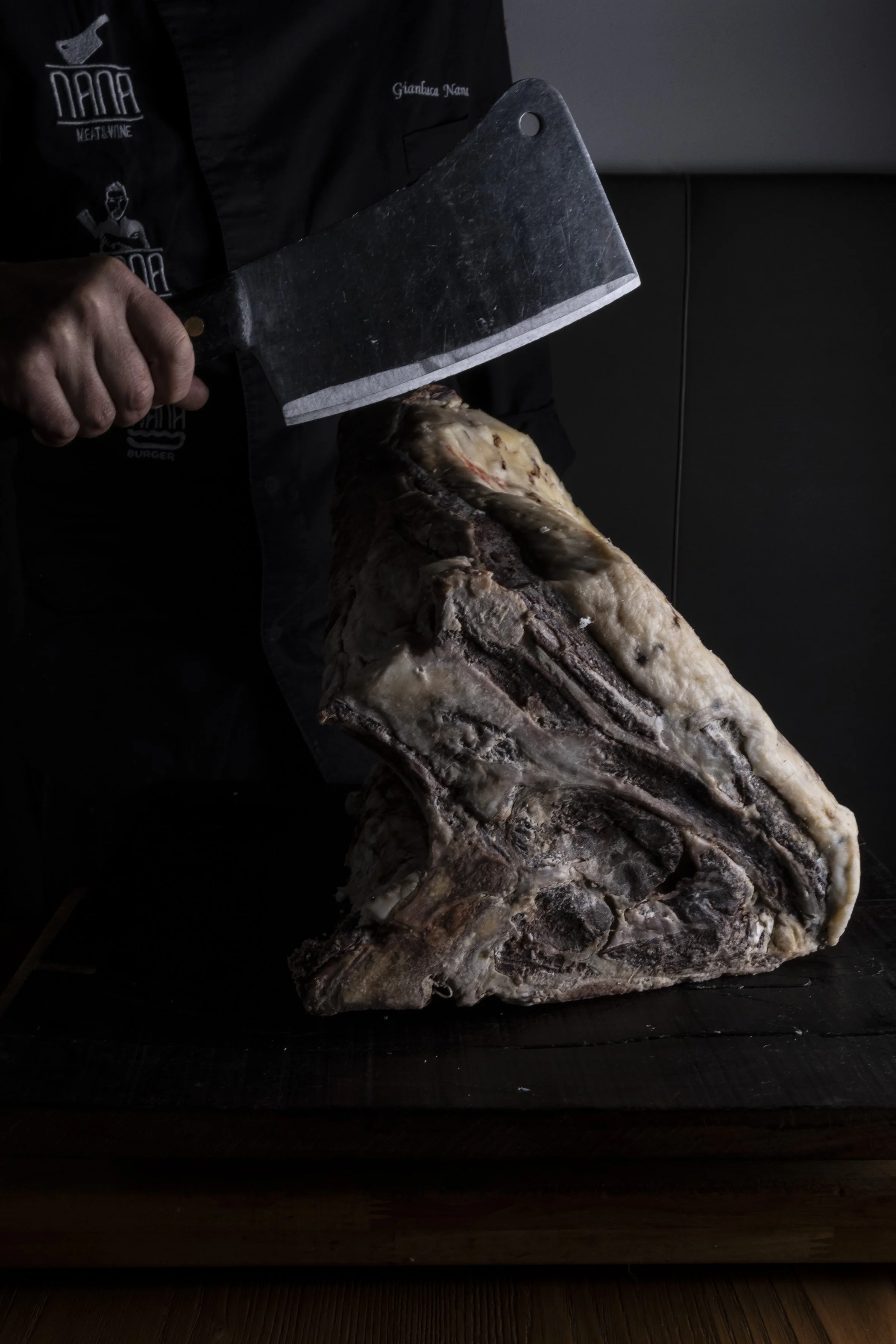 Un uomo che sta tagliando un grande pezzo di carne con un coltello da macellaio.