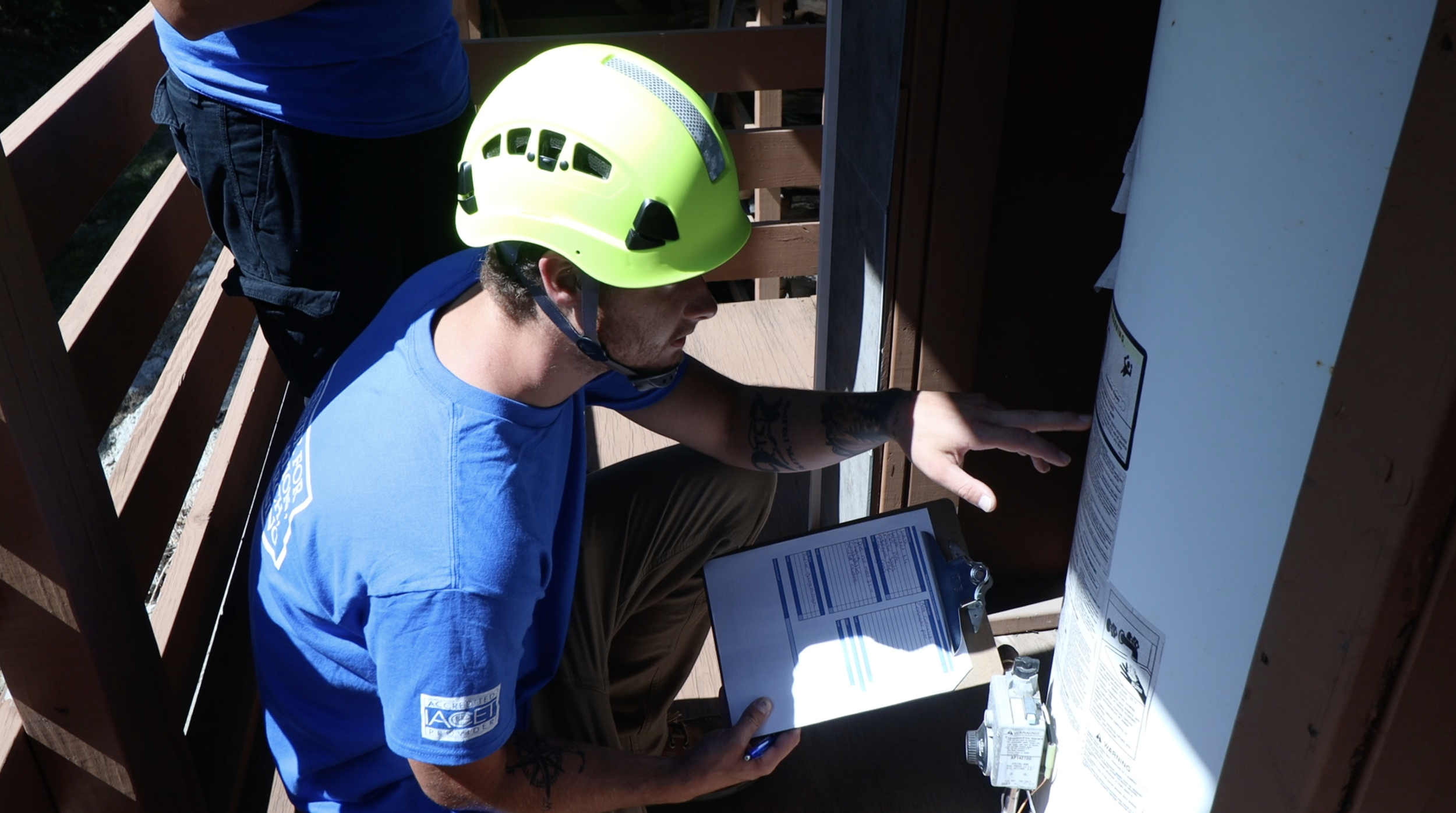 A student looking at a clipboard and reading the side of a pipe.
