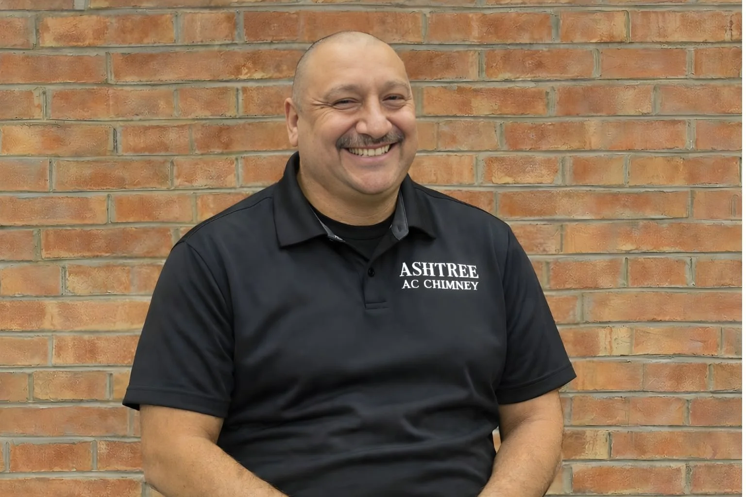 Robert Ornelas sitting in front of brick wall.