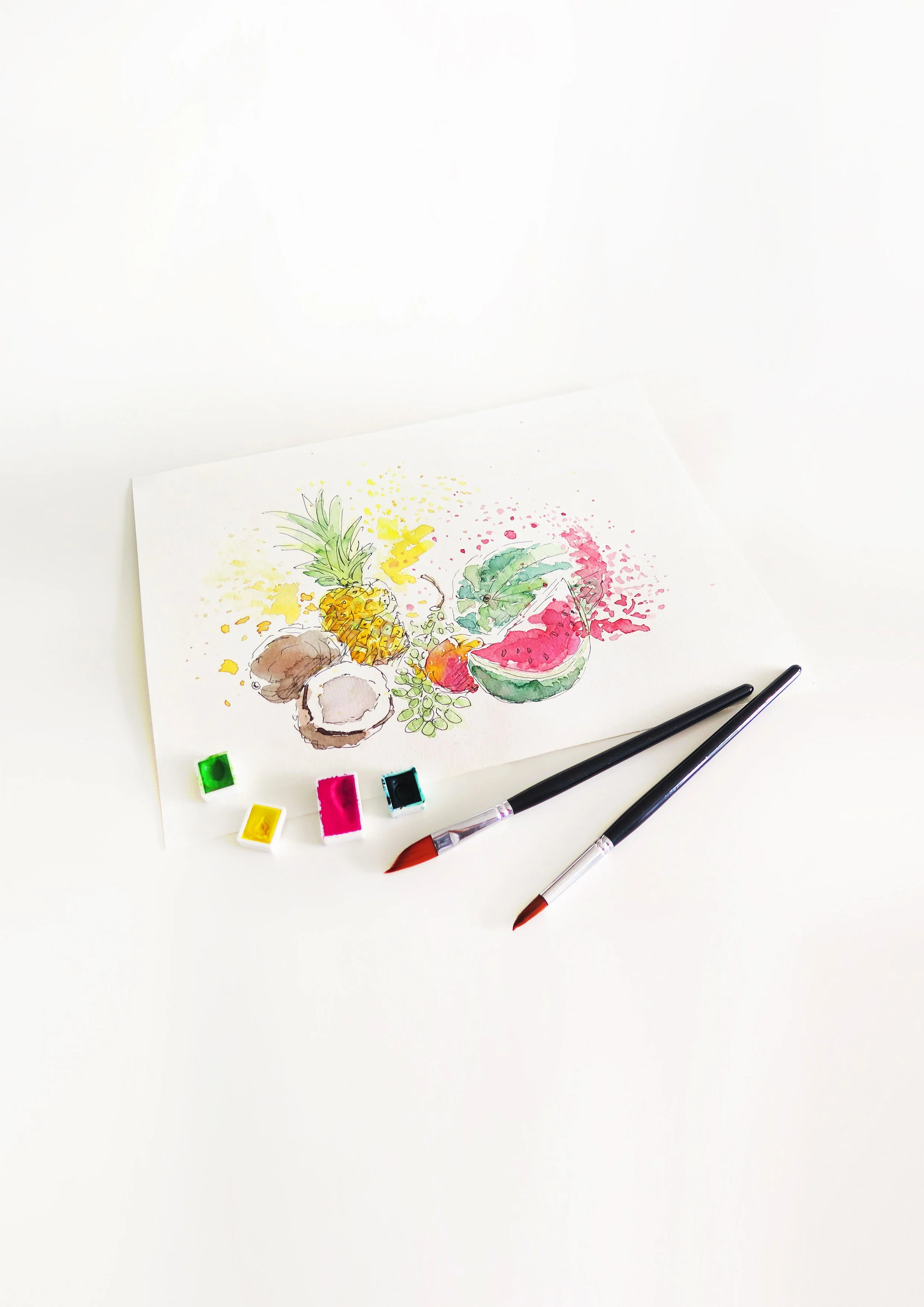 Watercolor painting of tropical fruits including pineapple, coconut, watermelon, and a leafy green plant, with two paintbrushes and watercolor paint pots on a white surface.
