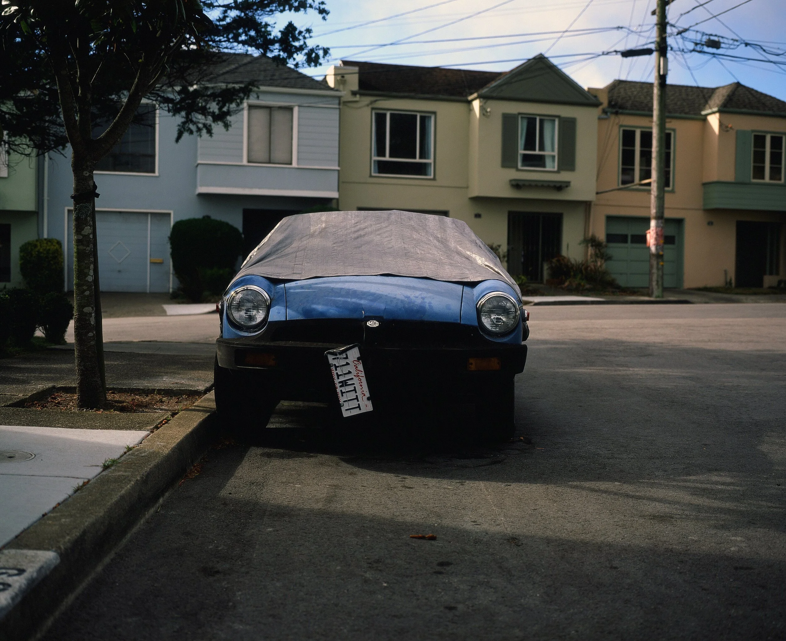 A street parked car with a hanging license plate In San Francisco in 2016