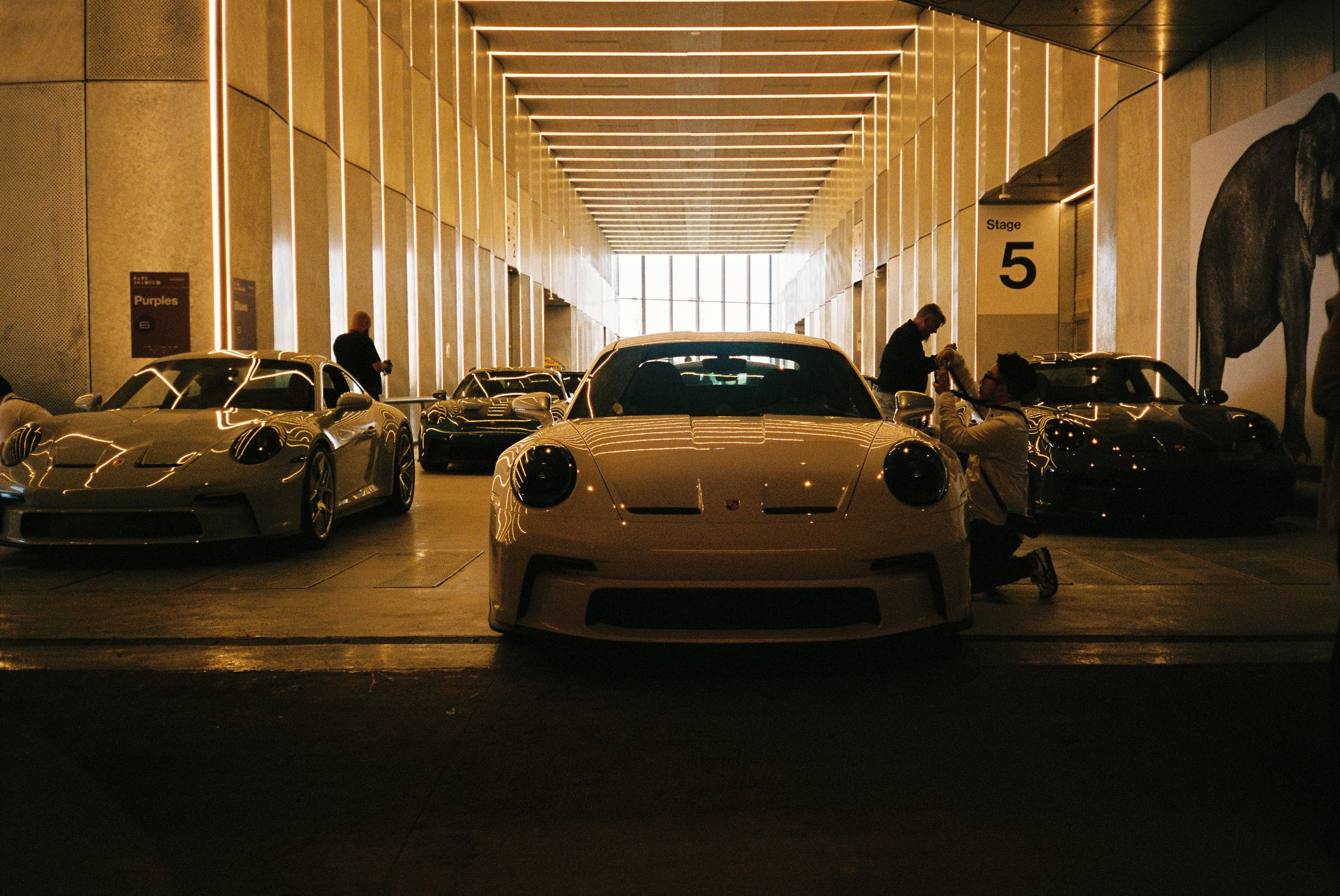 A front view of the main showroom of the event with multiple cars and people admiring and photographing them