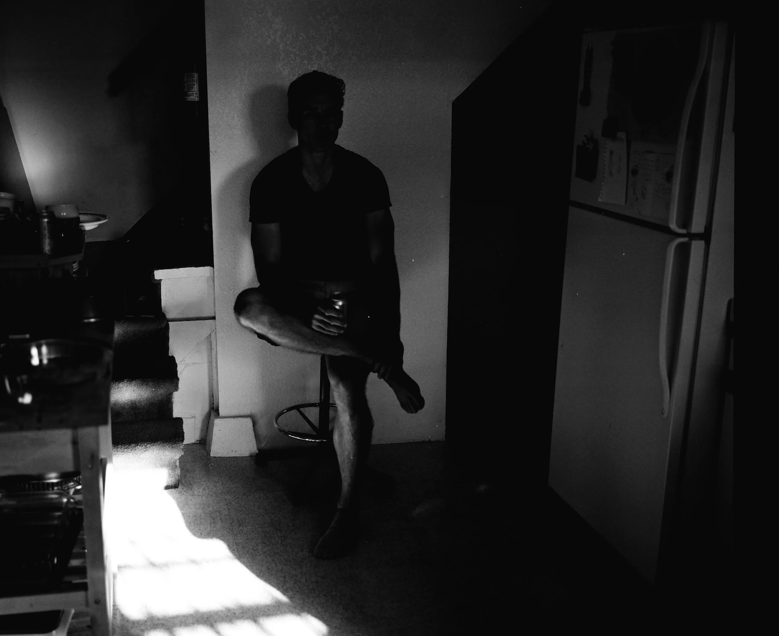 A guest sitting in the kitchen with a beer at a San Francisco house party in 2016