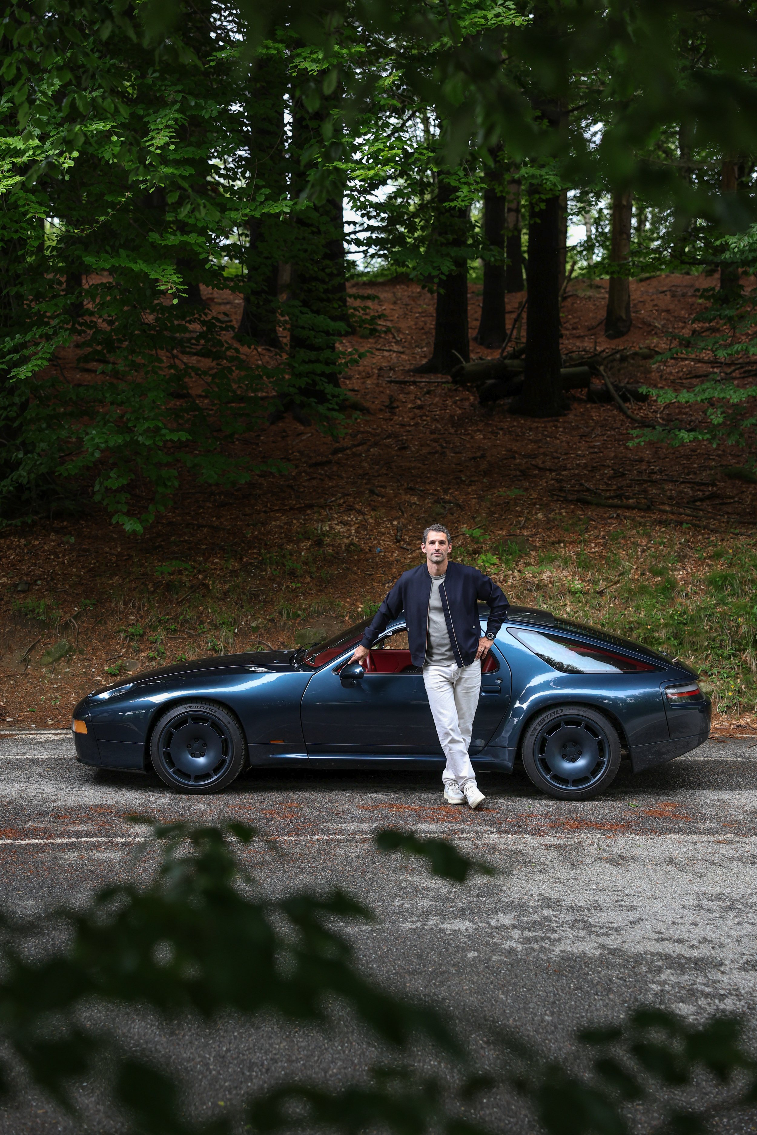 Thierry Nardone posing in front of his parked Nardone 928 on a road in the forest