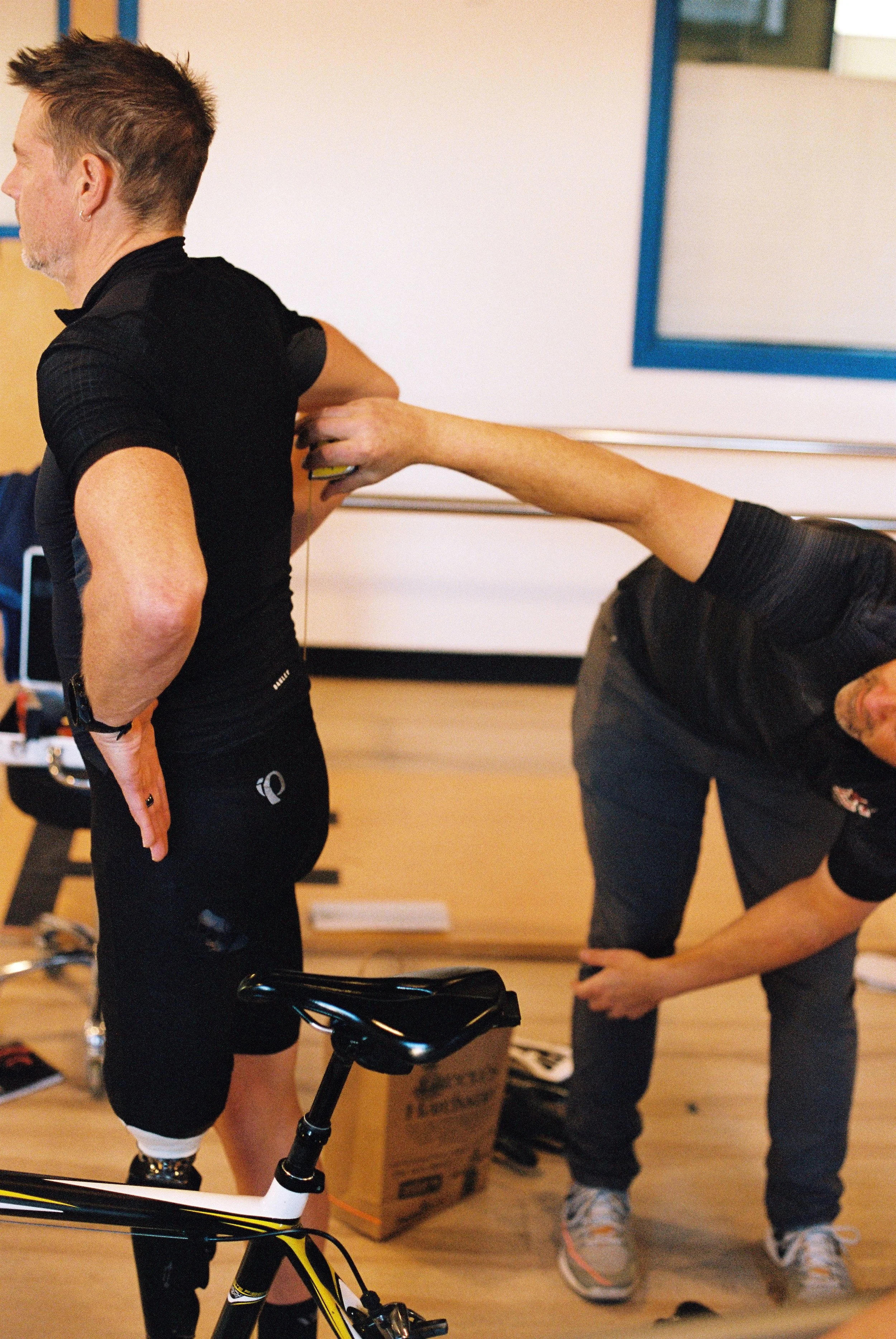 Mike takes some measurements of Dave's back while performing a bike fit in John's office