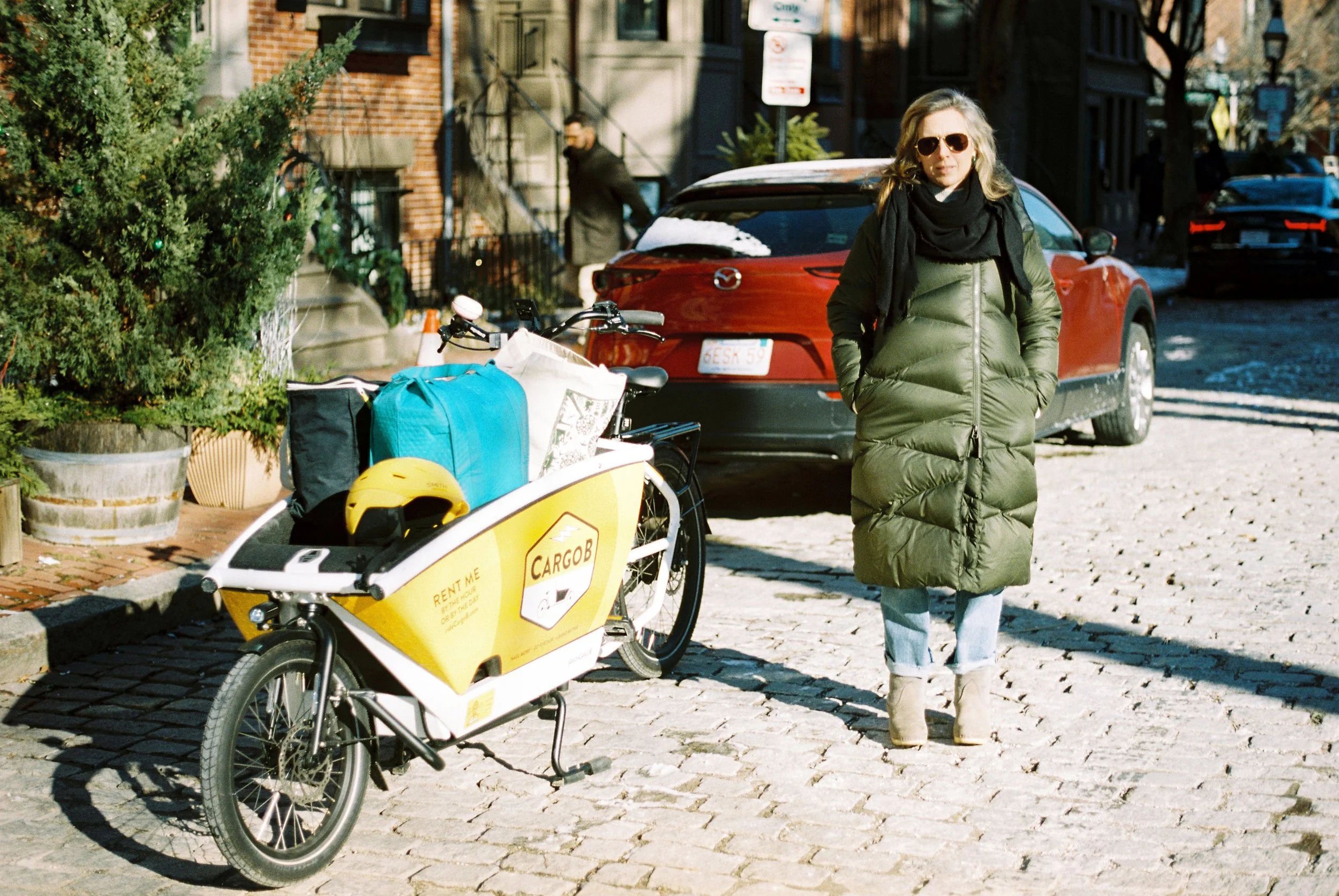 Dot Fennell posing next to a CargoB cargo bike filled with bags in Boston's South End