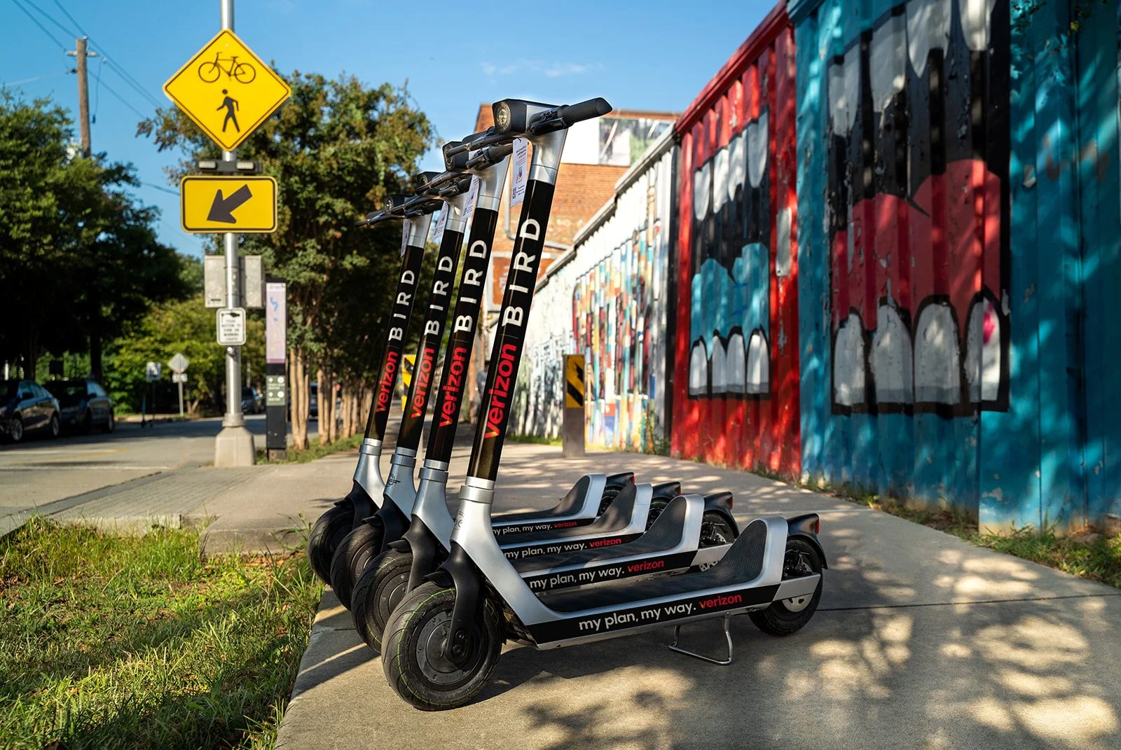 Bird Scooters Product Photography for Ad placements by Mushaboom Studio photographer Laura Grace Sears. Four scooters lined up in front of vibrant Atlanta graffiti. You can clearly see the Bird logo along with Verizon ad placement. 