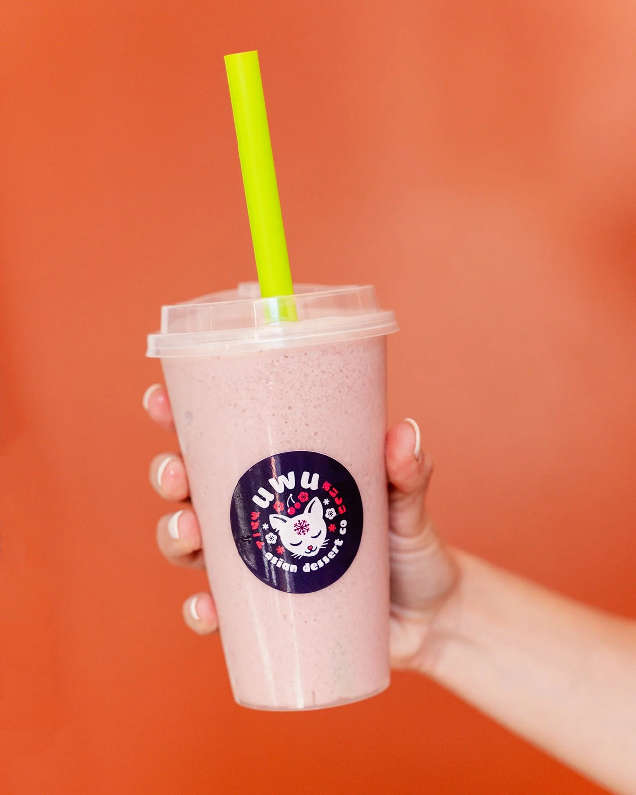 Uwu Bubble Tee in a hand in front of an orange wall at Ponce City Market.