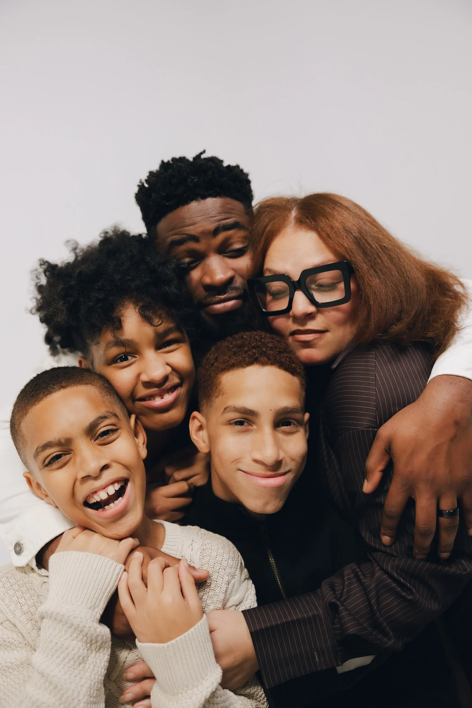 Group of diverse people, including children and adults, hugging and smiling together.