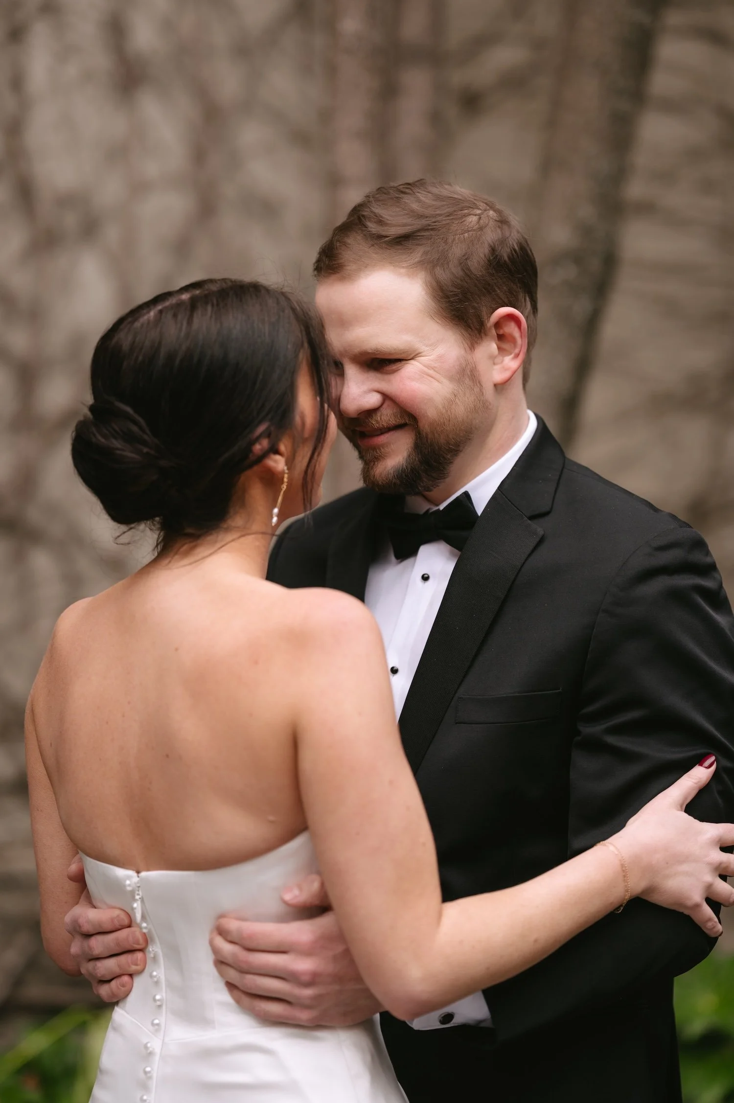 A bride and groom sharing an intimate dance outside, smiling and holding each other closely during their wedding celebration.