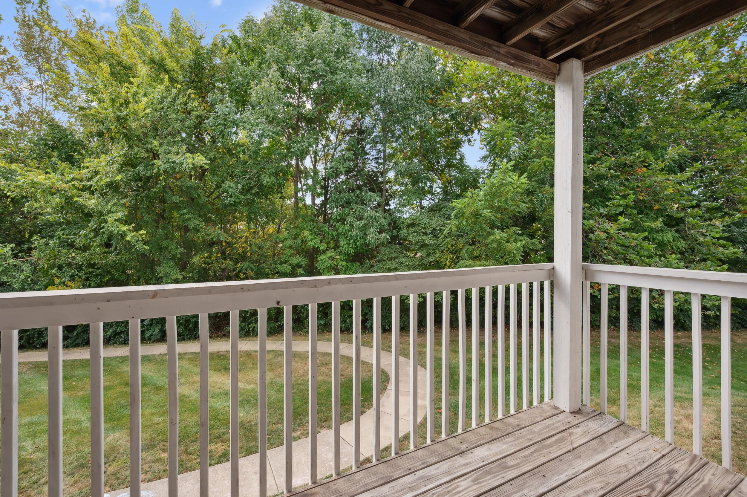 Image of Honey Creek Balcony with a wooden deck area, wooden peg railing and roof overhang overlooking the nature trail walking path