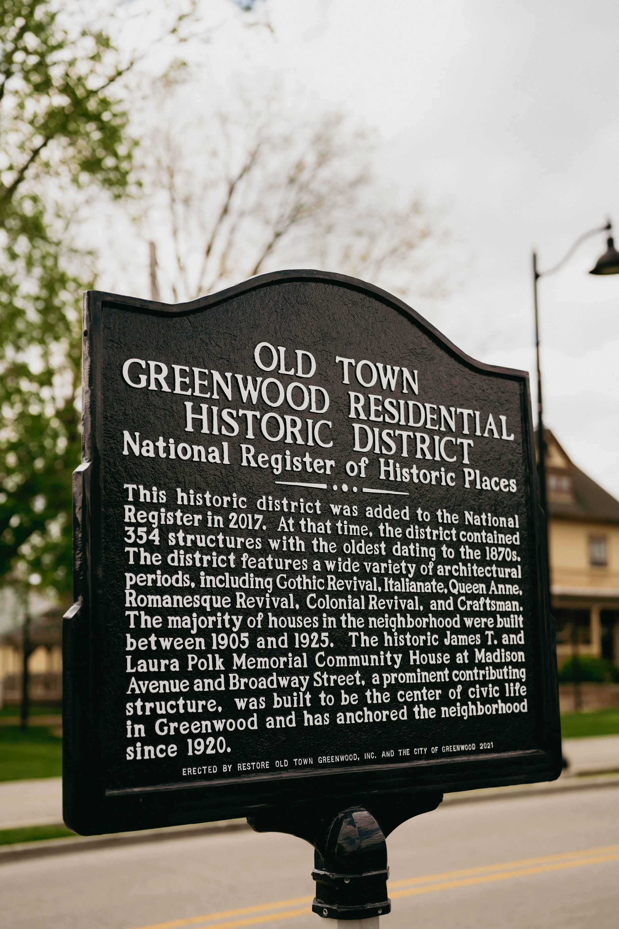Historical district informational sign in Greenwood, featuring text about the district's addition to the National Register of Historic Places, its architectural styles, and significant buildings.